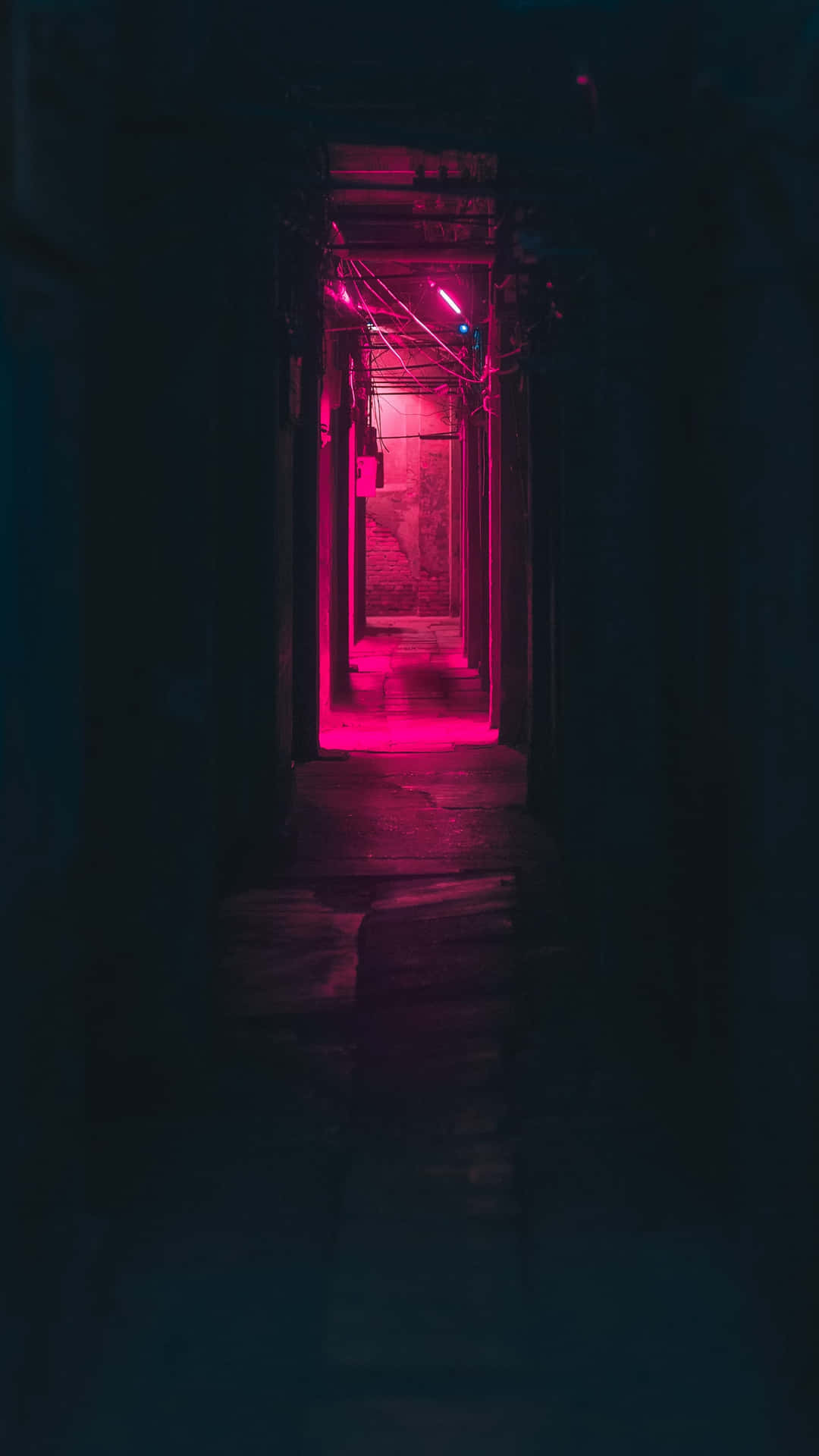 一條狹窄的小巷，夜晚被粉紅色霓虹燈照亮。