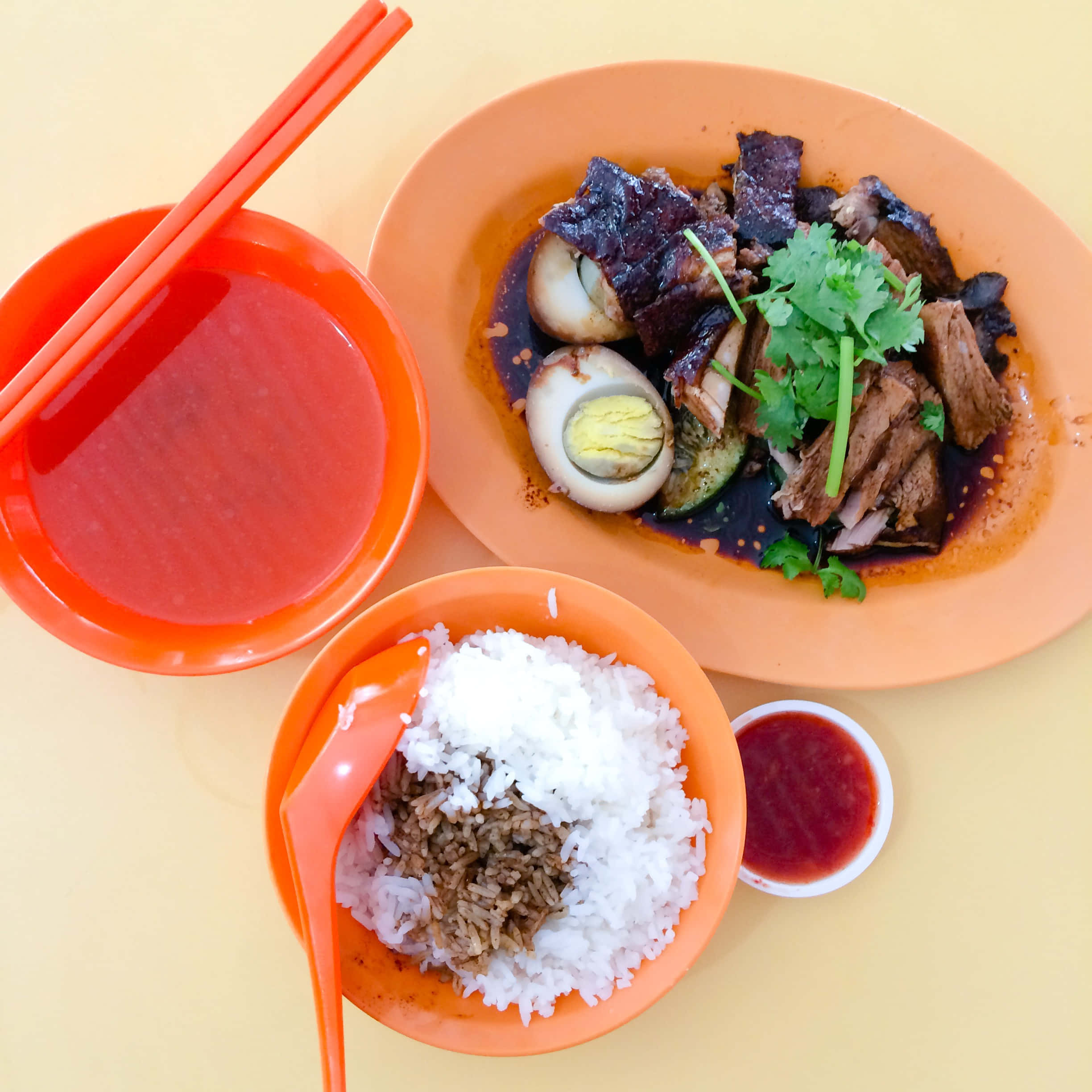 醬汁滷鴨飯 壁紙 — 俯視一個充滿活力的橙色碟子，上面有燉肉和香草，旁邊有碗飯和湯，還有筷子。