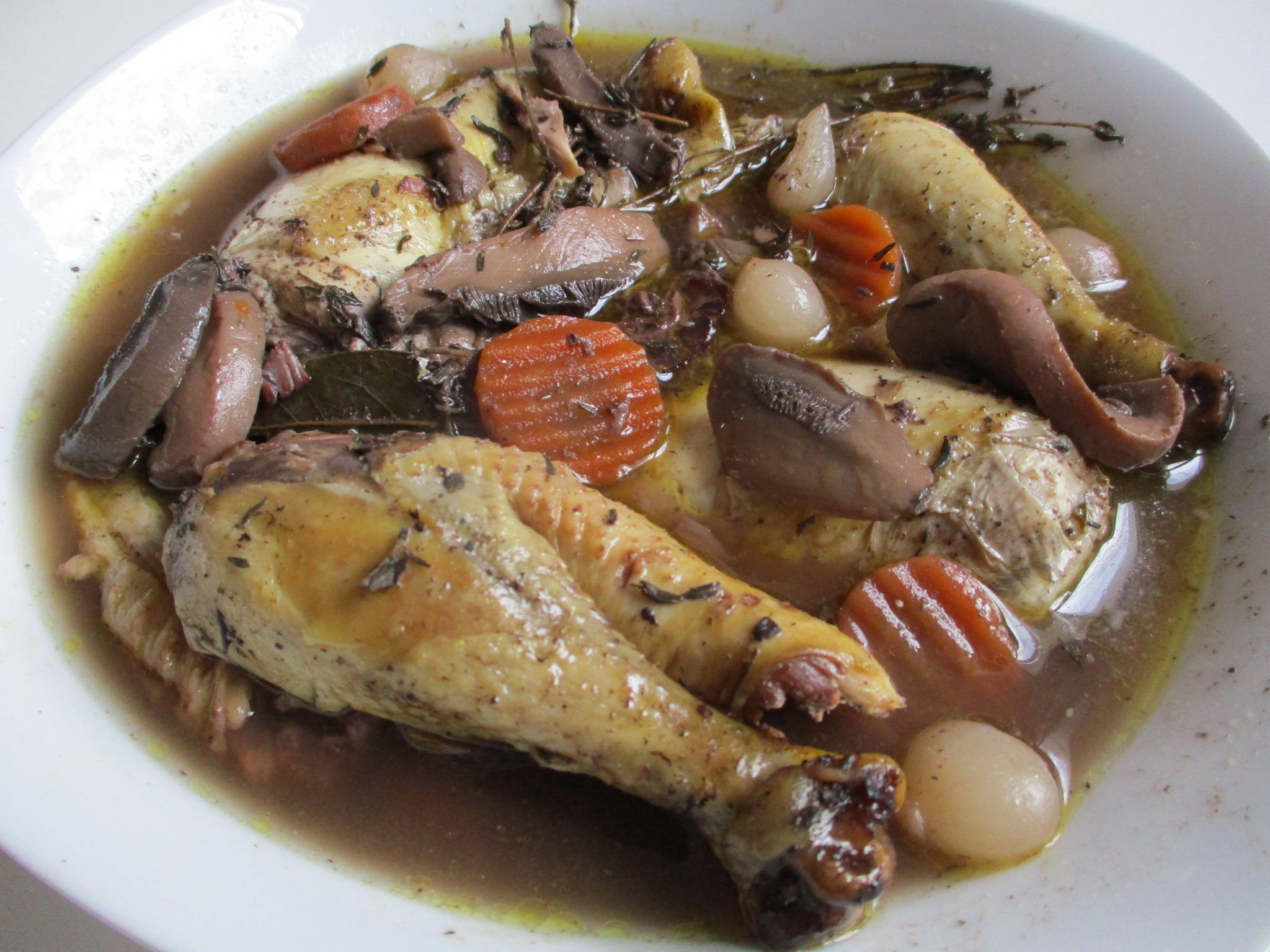 醬汁豐盛的Coq Au Vin 壁紙 — 一碗豐盛的雞肉燉菜，搭配紅蘿蔔、蘑菇和珍珠洋蔥，在濃郁高湯中慢燉。