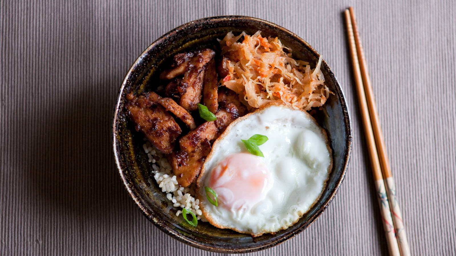 醬燒雞肉配蛋的炒飯 壁紙 — 一碗鄉村風格的米飯，上面放有釉面肉泡菜和太陽蛋，並以青蔥裝飾。