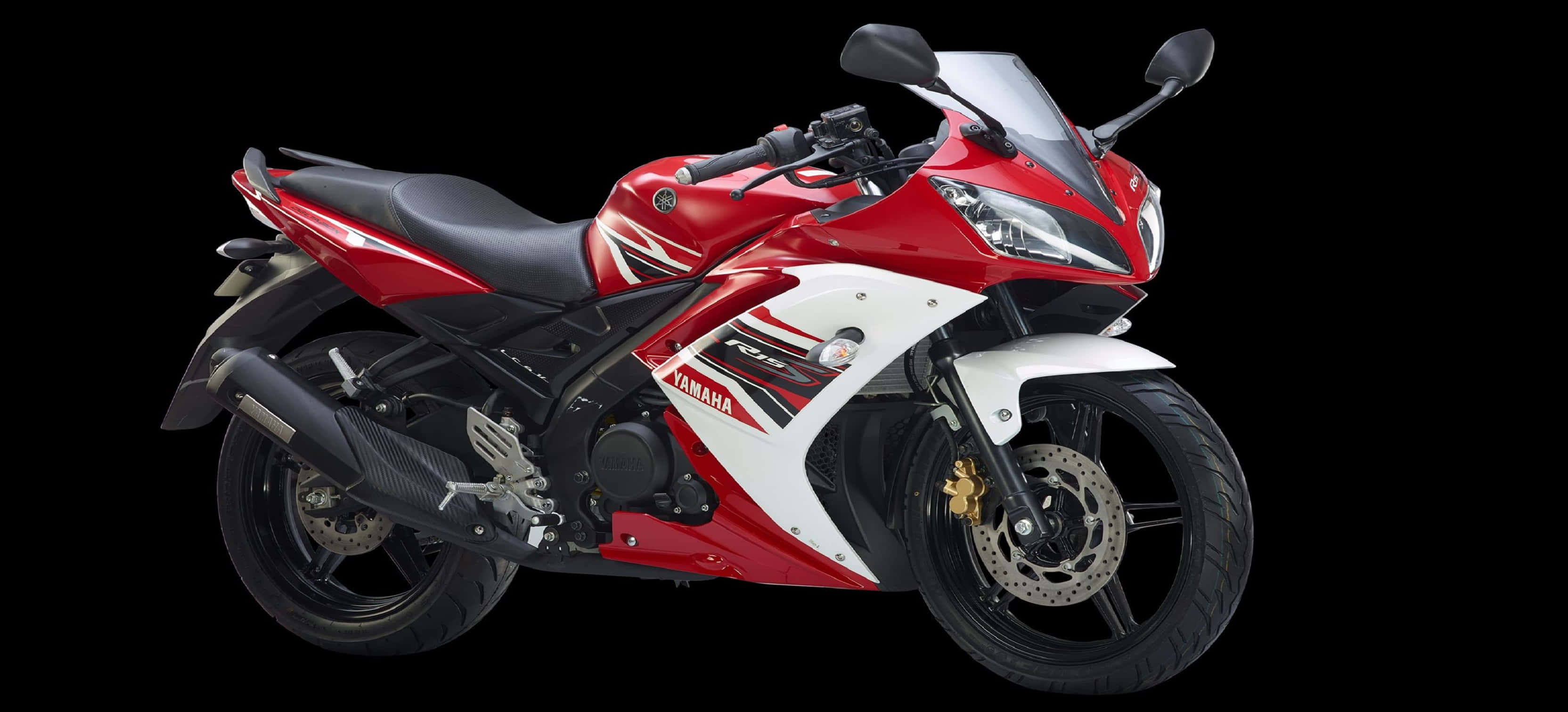 釋放 R15 的強勁動力 壁紙 — 一架流線型紅白Yamaha R15運動電單車，帶有黑色點綴和金色制動卡鉗，在純黑色背景上孤立展示。