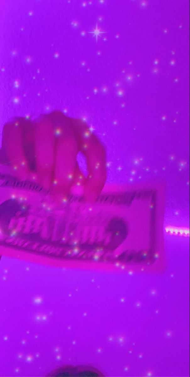 一隻手在星空紫色天空下拿著發光的粉紅色糖果棒。