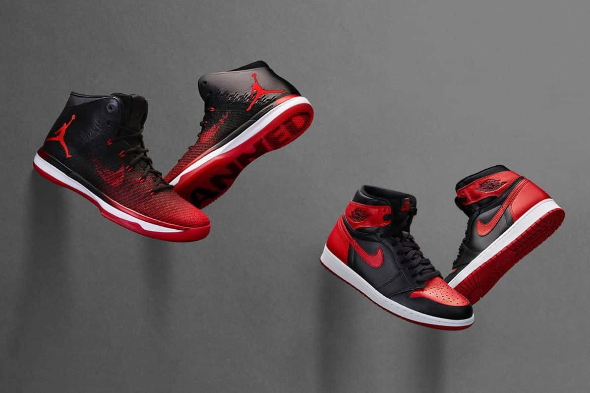 釋放內在 Hypebeast，掌握最新時尚趨勢 壁紙 — 兩對黑色和紅色的Jordan運動鞋在灰色中性工作室背景上動態漂浮。