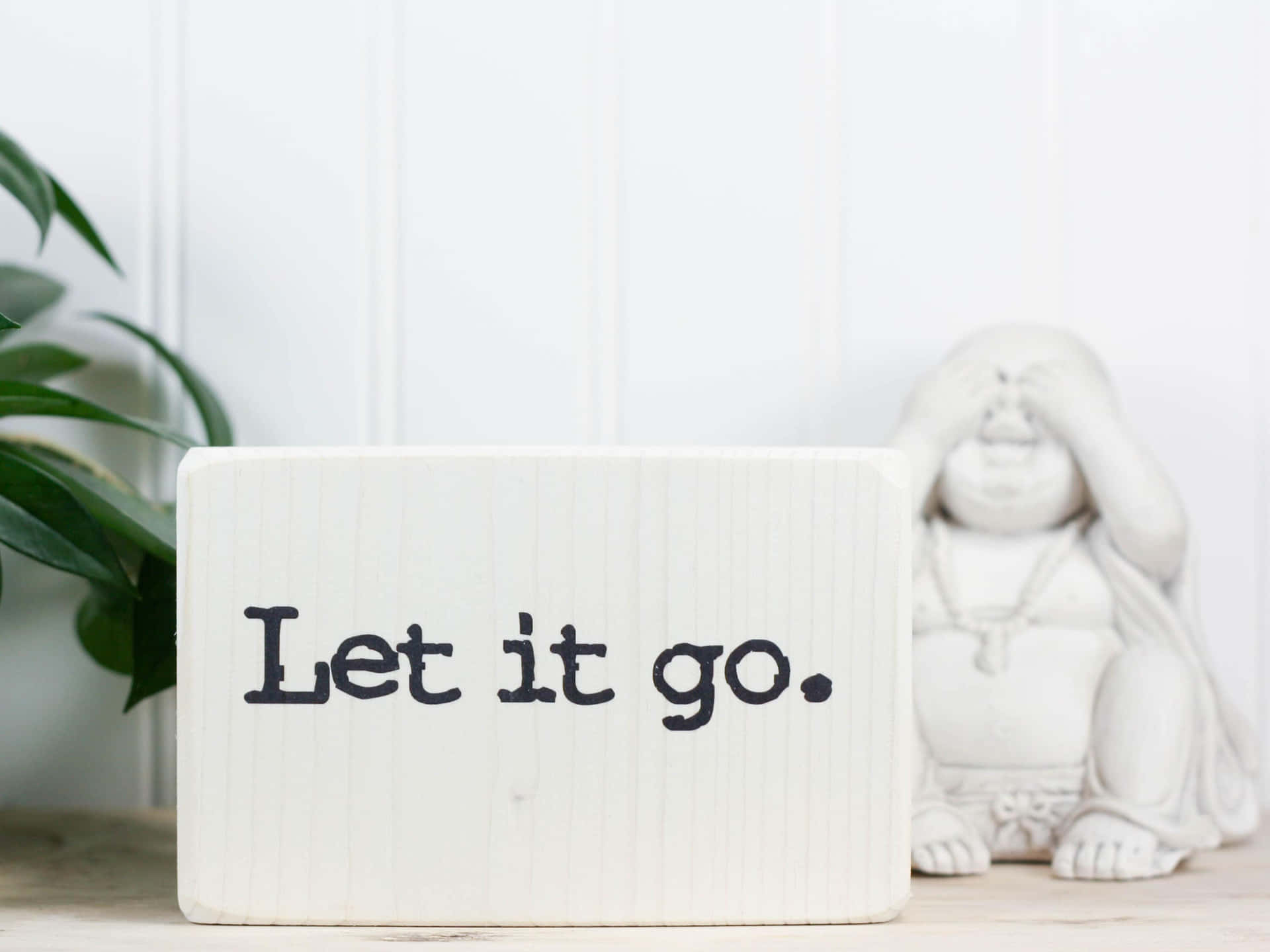 白色木塊上寫著 Let it go，旁邊有佛像和綠色植物。