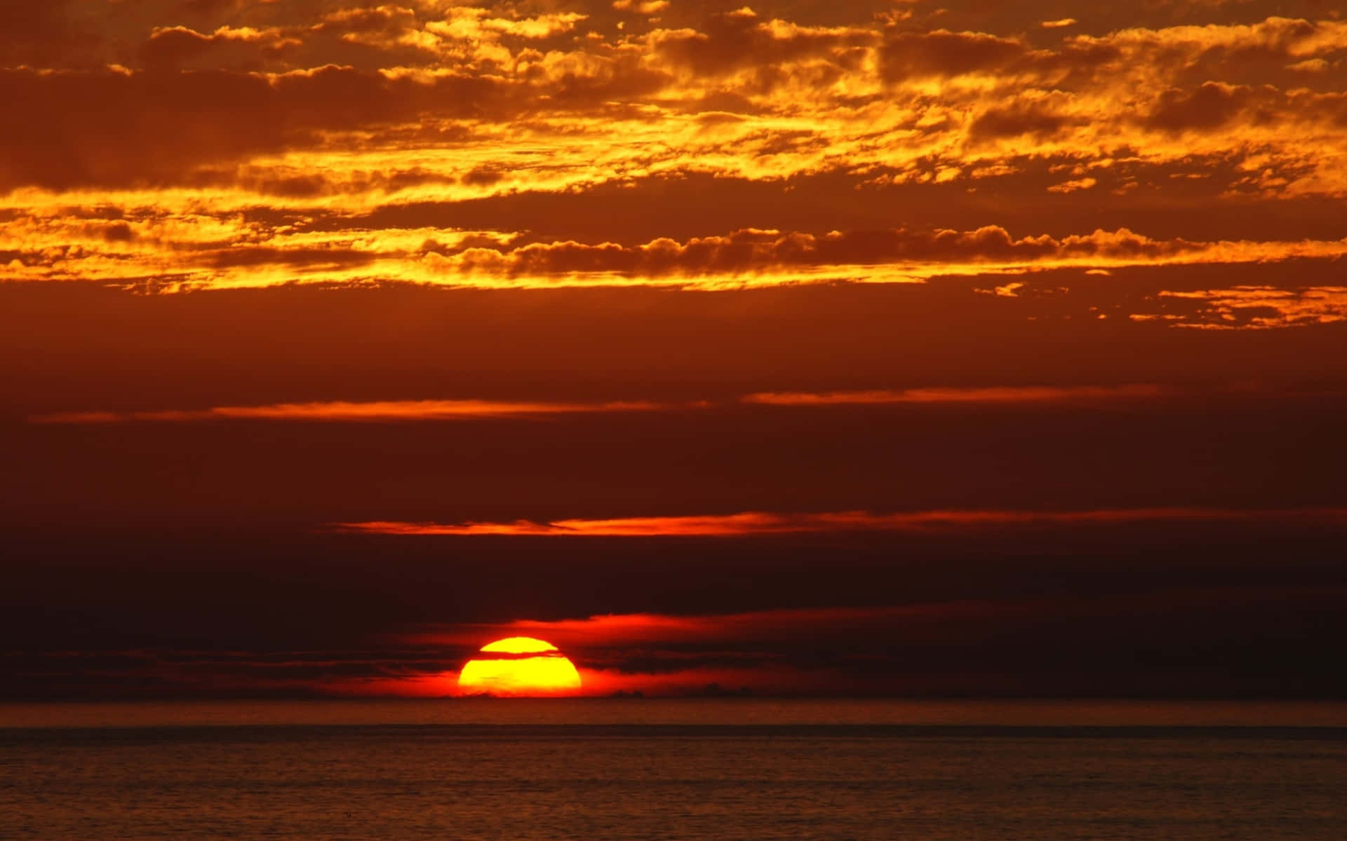 海洋上的夕陽，帶有熾熱的橙色和紅色雲彩