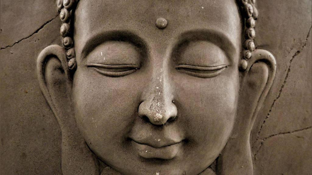 寧靜的石佛頭，閉著眼睛，有肉髻，背景是裂縫牆壁。