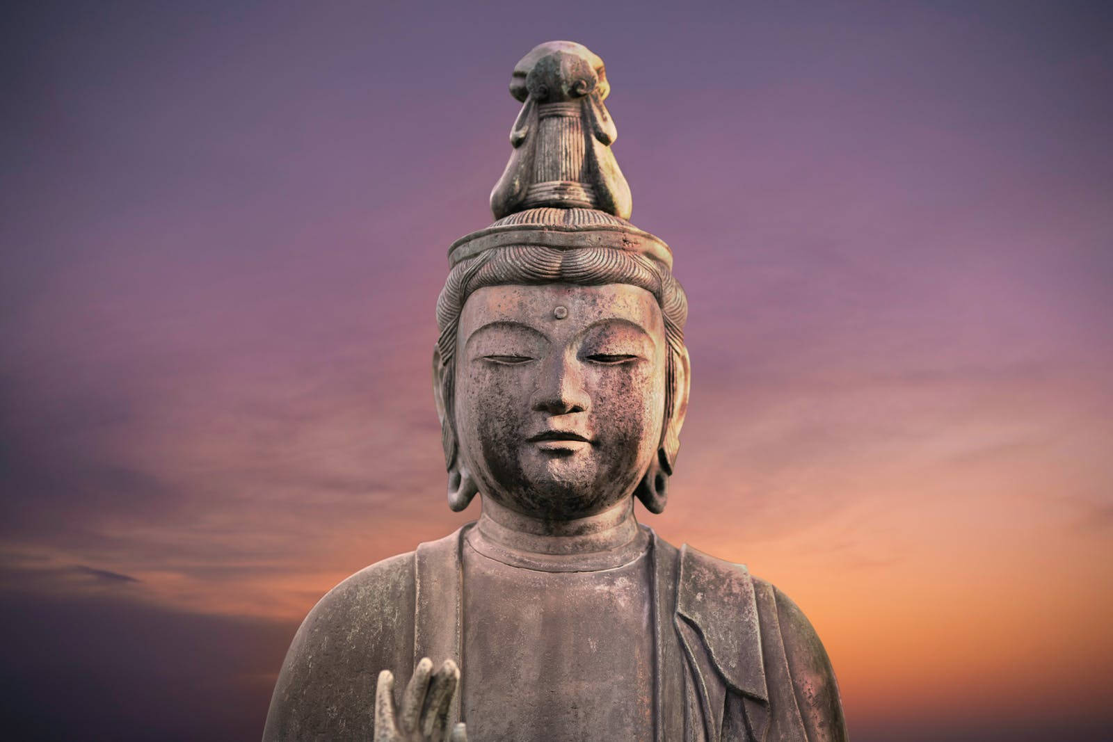 寧靜石佛像，頭頂獅子，暮色天空背景。