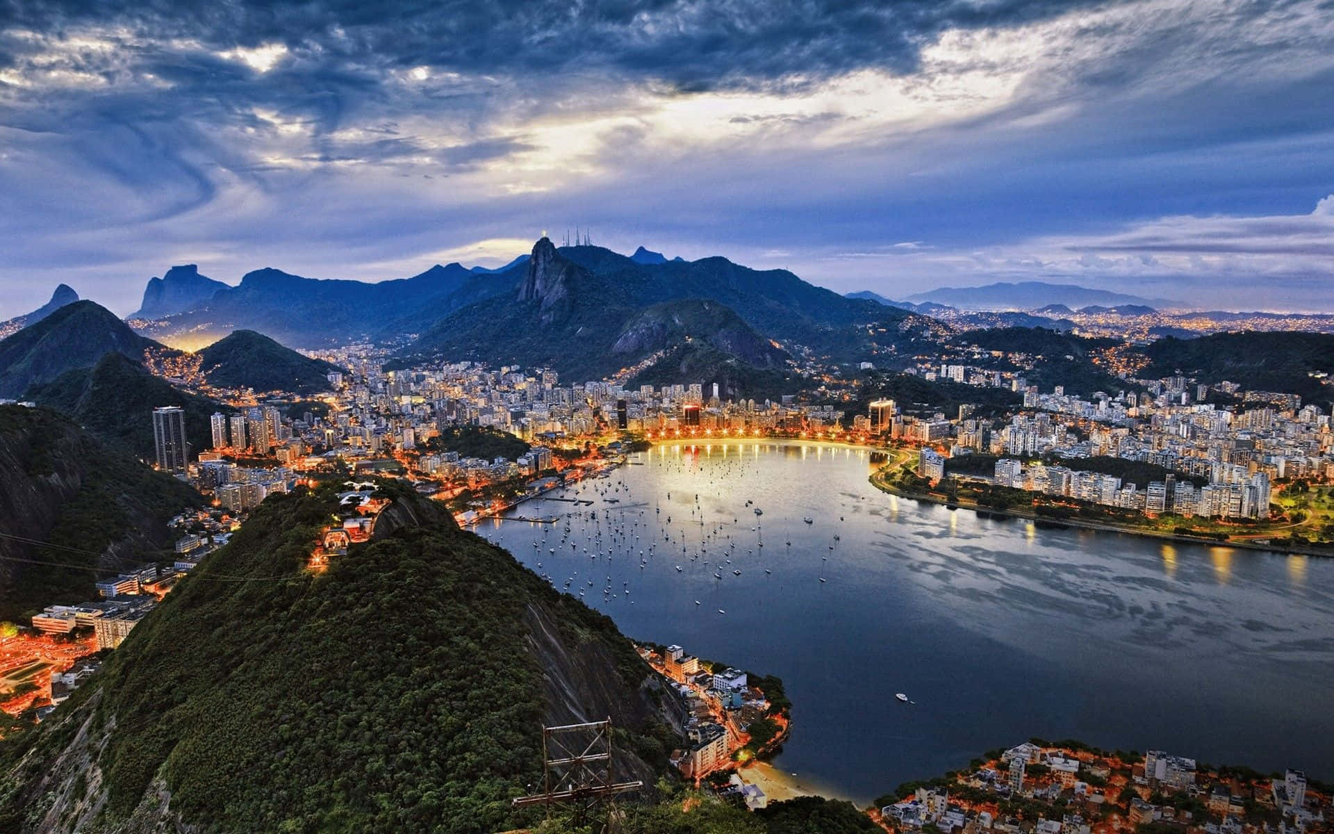 Brazil 桌布 壁紙 — 里約熱內盧令人驚嘆的黃昏景色，閃爍的城市燈光倒映在被茂密山脈環繞的瓜納巴拉灣上。