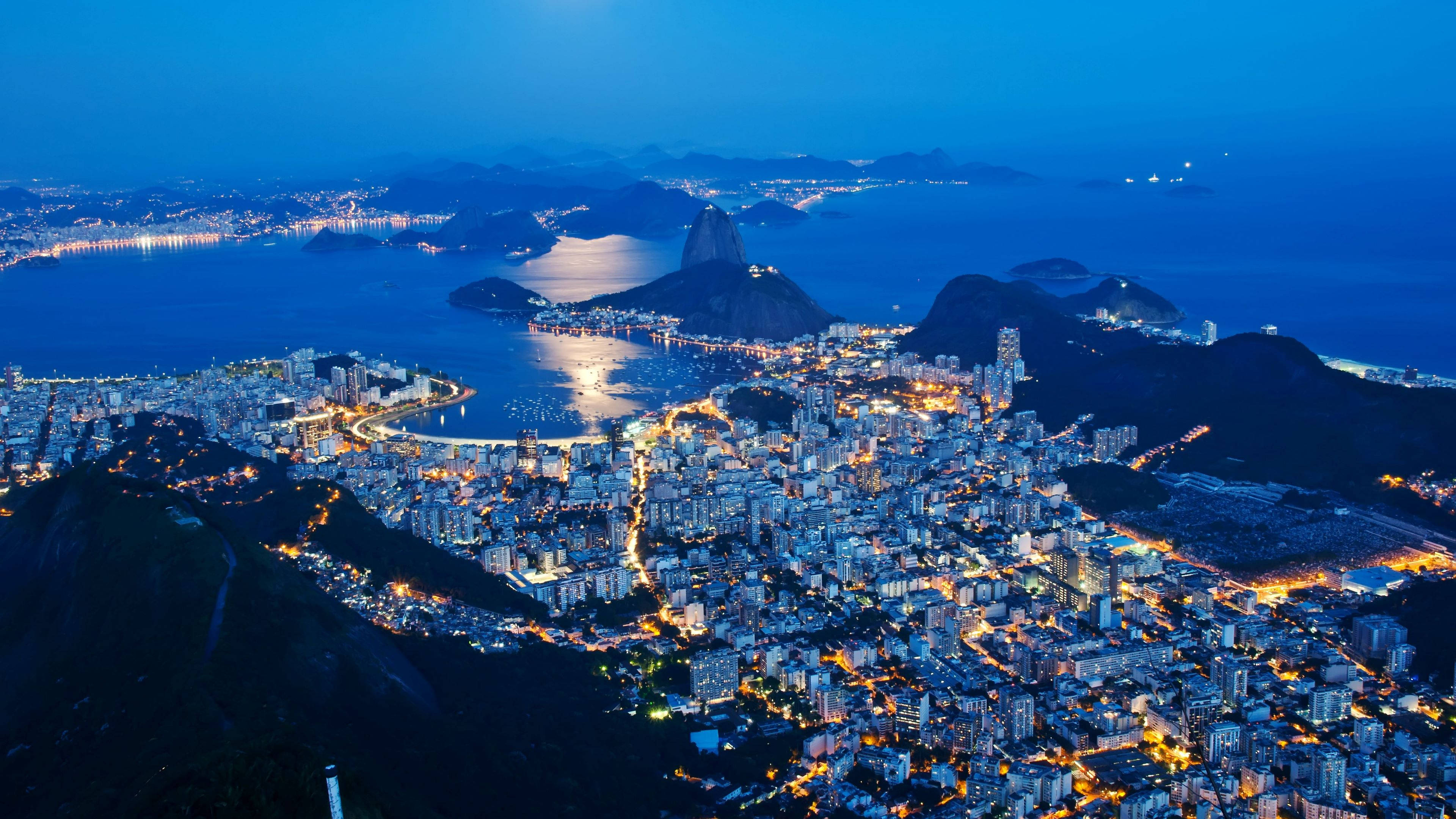 里約熱內盧城市夜景 壁紙 — 里約熱內盧黃昏時的鳥瞰圖，糖麵包山和城市燈光在深藍色天空中閃耀。