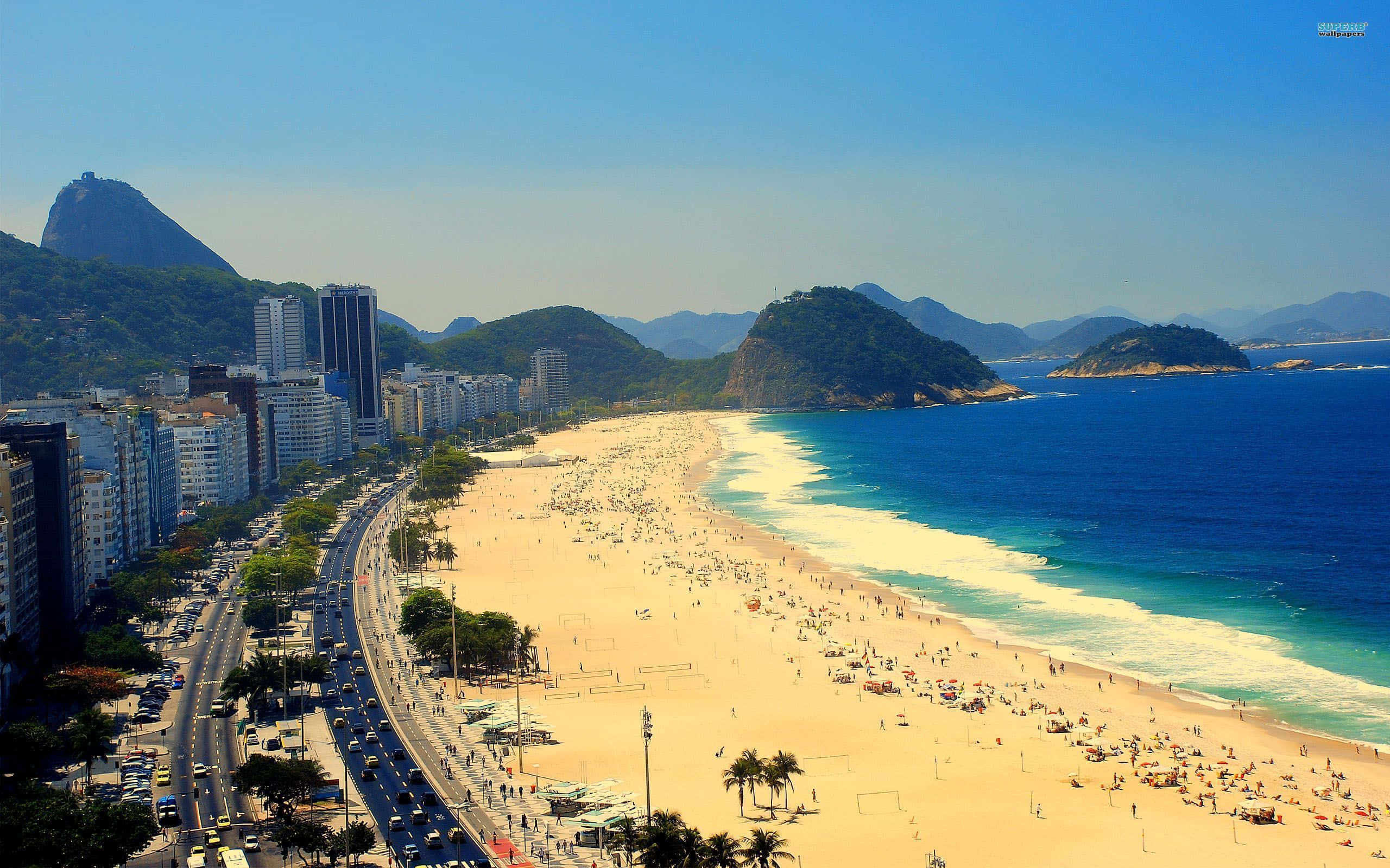 Brazilian Beach 桌布 壁紙 — 里約熱內盧科帕卡巴納海灘的鳥瞰圖，金色沙灘人潮擁擠，碧綠海洋，背景中的甜麵包山在清澈藍天下。