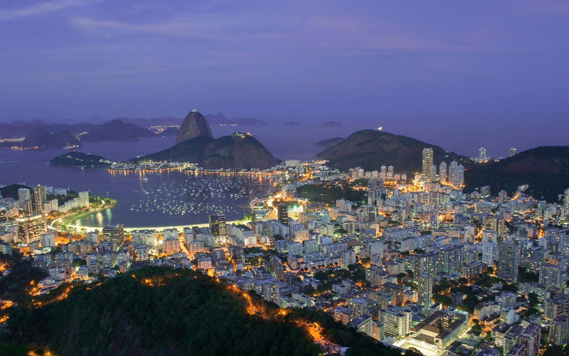 Brazil 桌布 壁紙 — 里約熱內盧黃昏時的鳥瞰圖，甜麵包山和基督像在紫色天空下亮起。