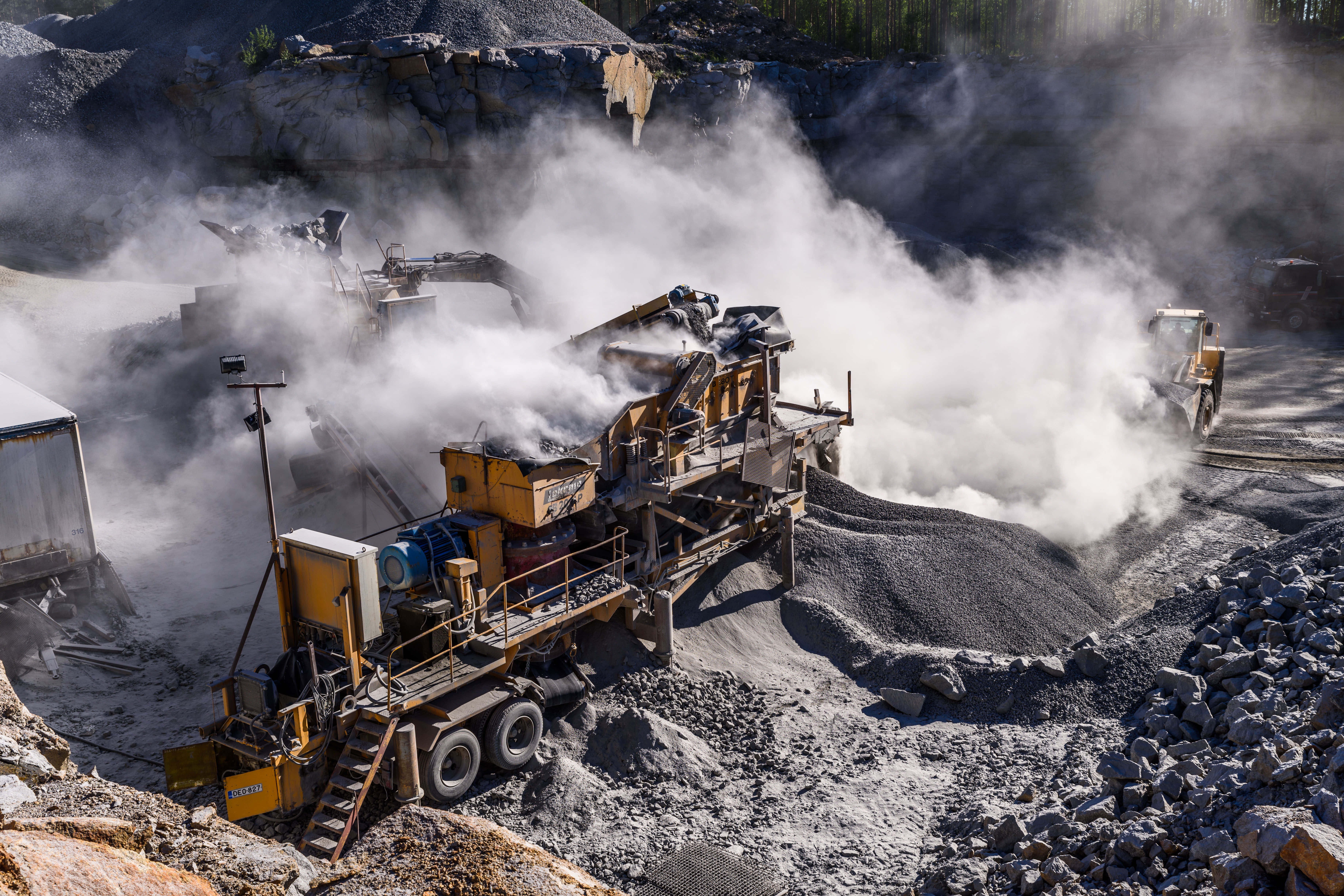 Mining 桌布 壁紙 — 重型機械在塵土飛揚的採石場處理礫石，活躍的設備在明亮的陽光下冒出蒸氣。