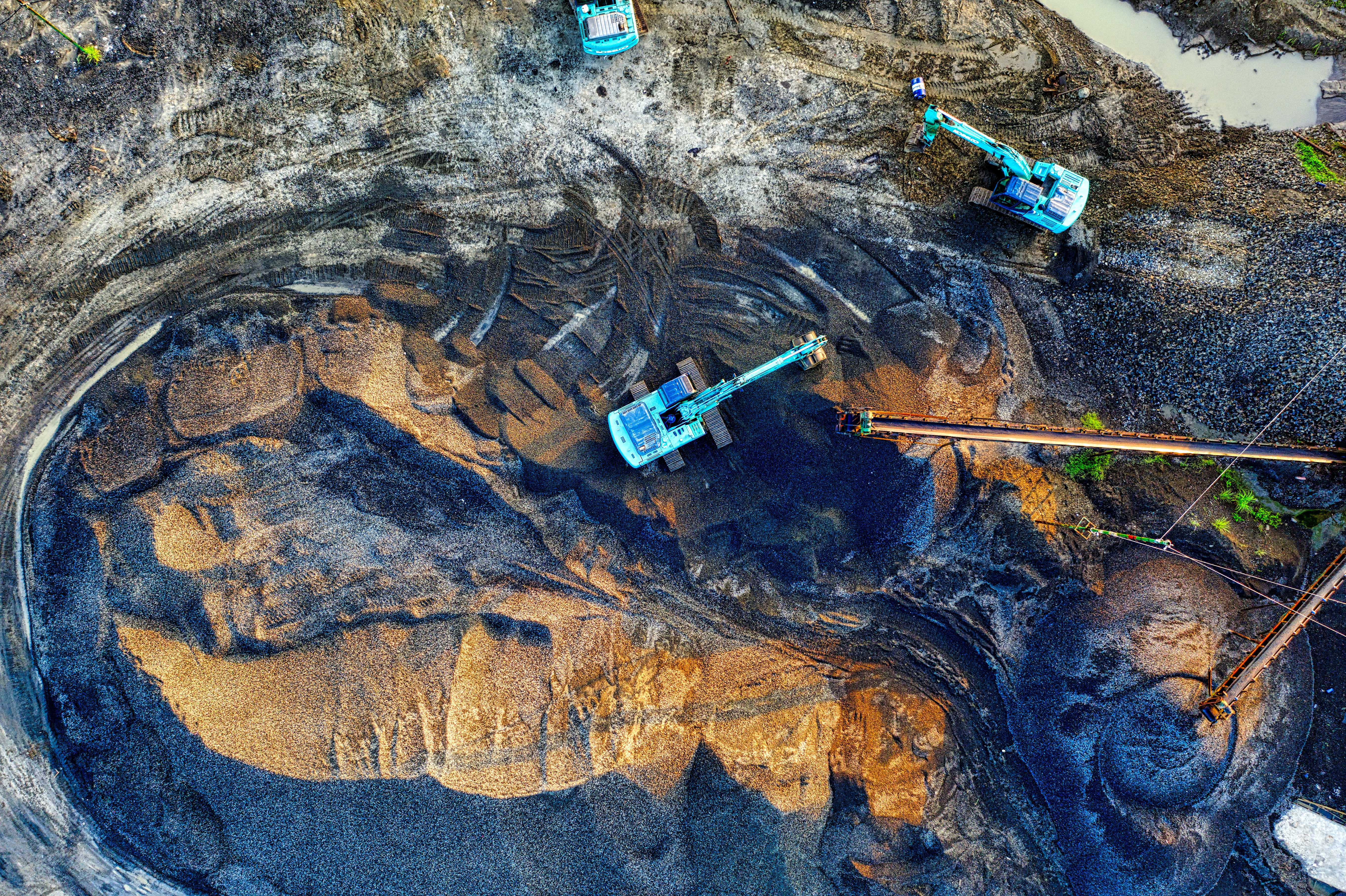 Mining 桌布 壁紙 — 重型機械在廣闊露天礦場作業的航拍視圖，呈現層層泥土色調與深邃陰影。