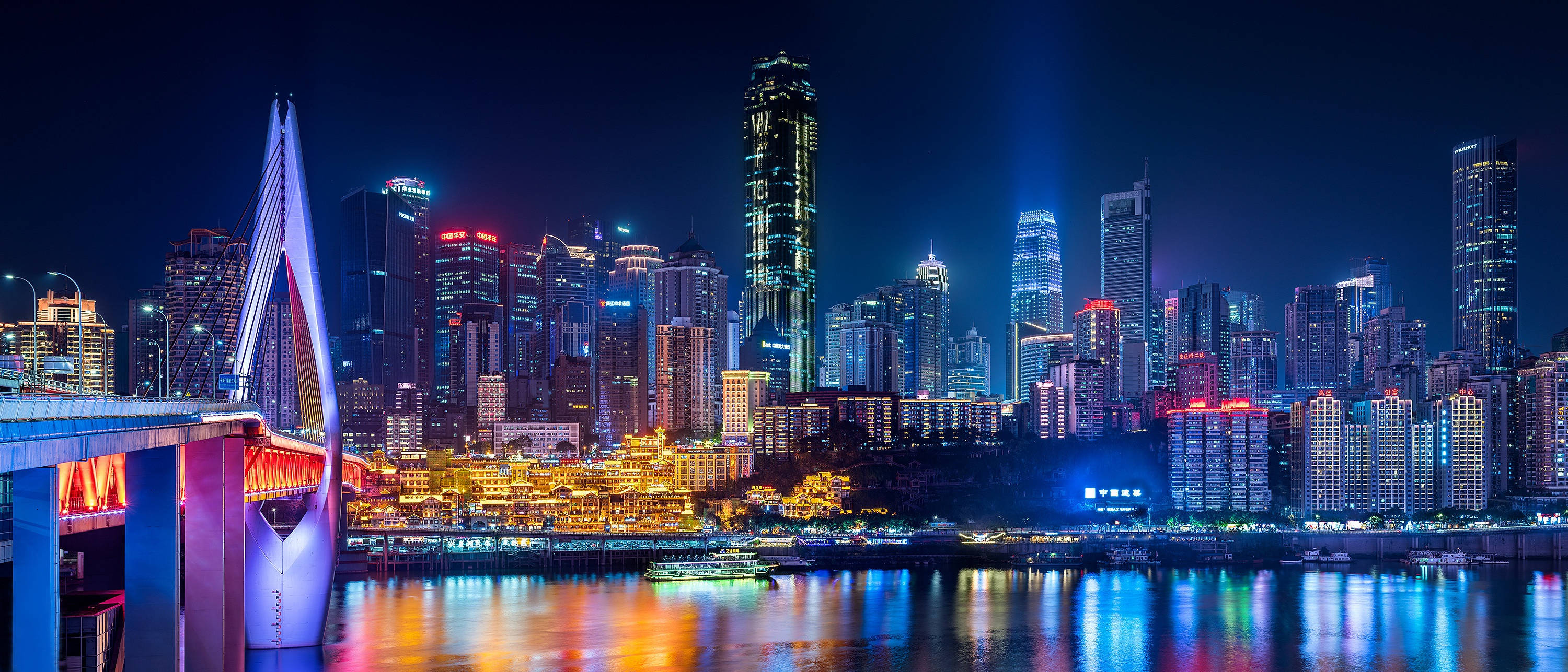 重慶夜景璀璨天際線 壁紙 — 璀璨的夜景城市景觀，發光的橋樑和摩天大樓倒映在下面的河流中。