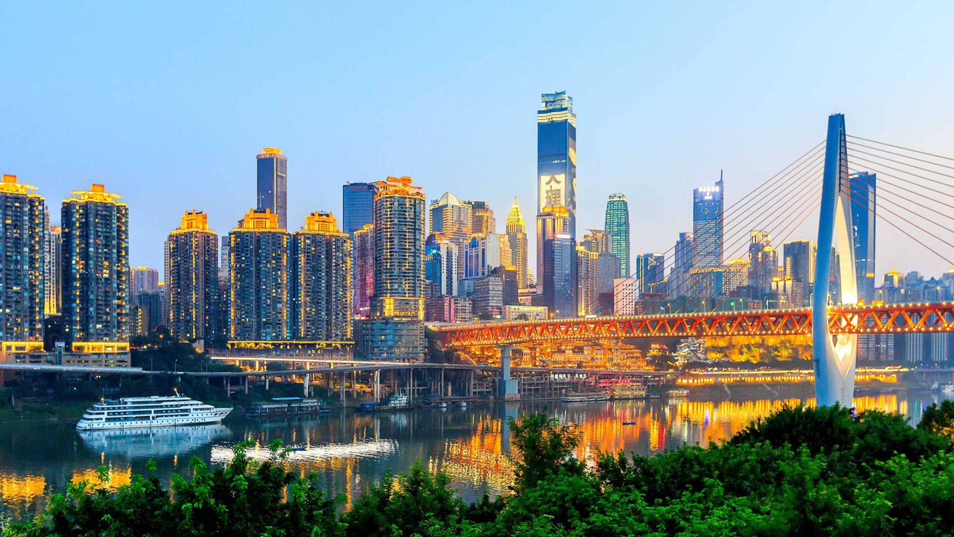 重慶摩天大樓霓虹夜景 壁紙 — 黃昏時分充滿活力的城市景觀，閃爍的摩天大樓和一座紅色橋樑倒映在平靜的水面上。