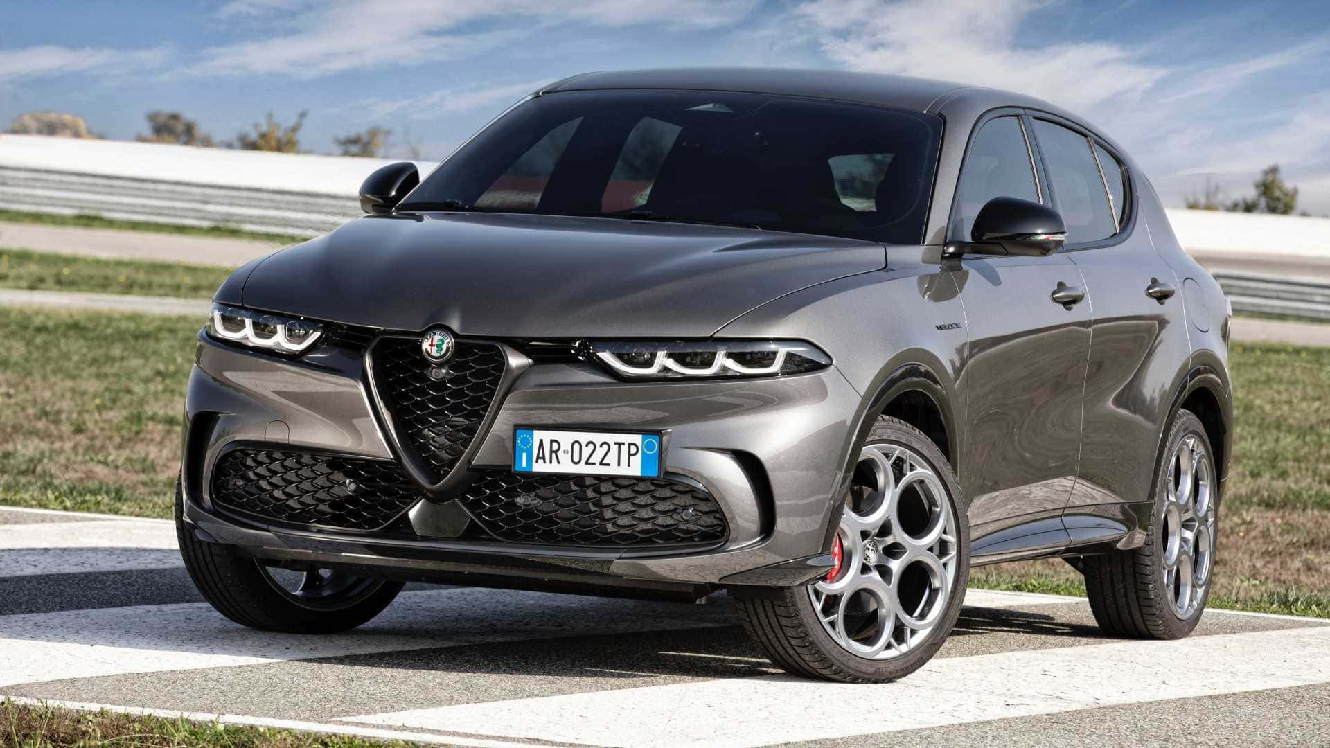 重新定義優雅——Alfa Romeo 花海盛放 壁紙 — 一架時尚的灰色Alfa Romeo SUV停泊在賽車場上，背景是晴朗的藍天和白色護欄。