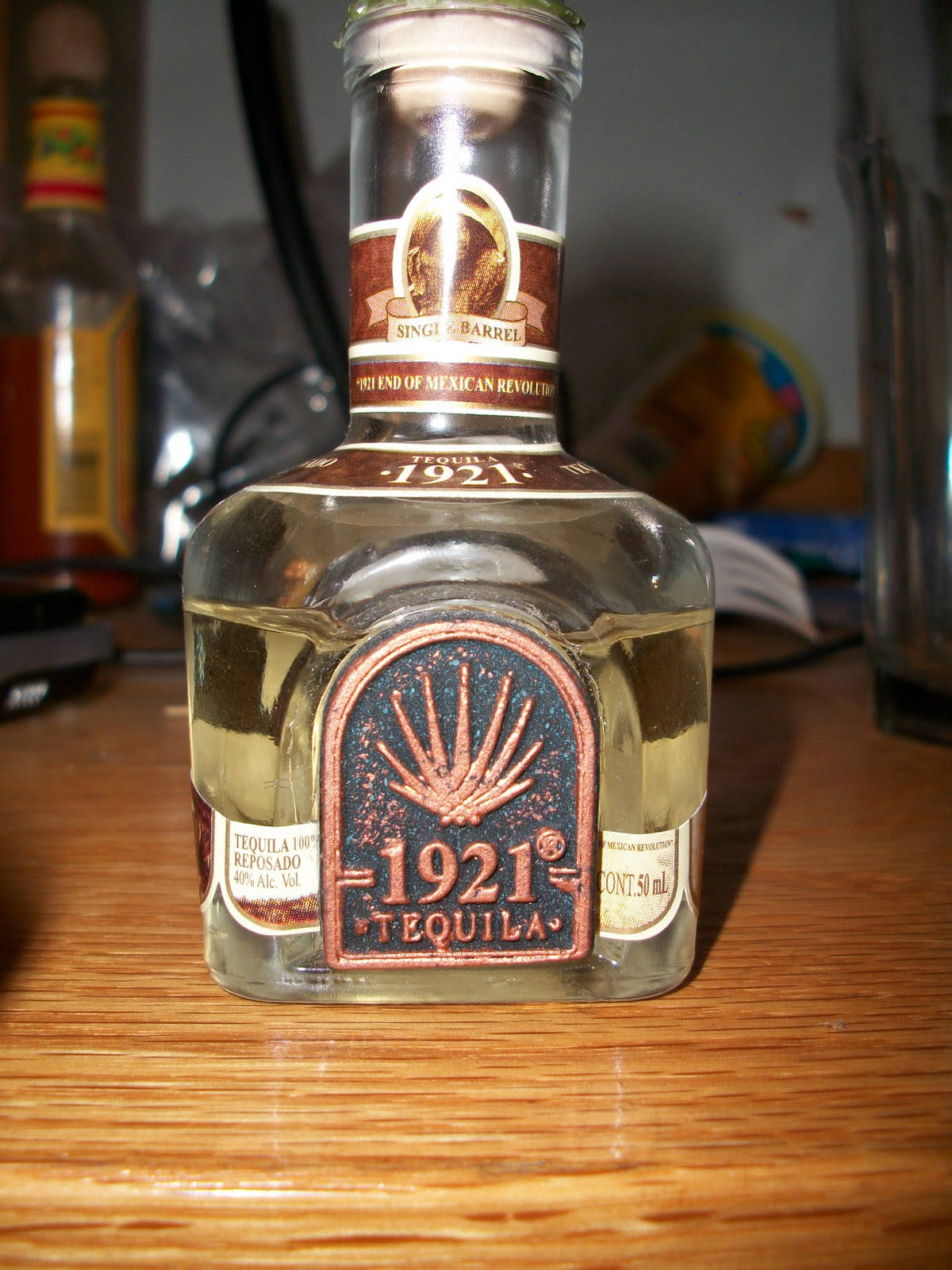 在昏暗房間的木桌上，一個1921 Tequila reposado酒瓶。