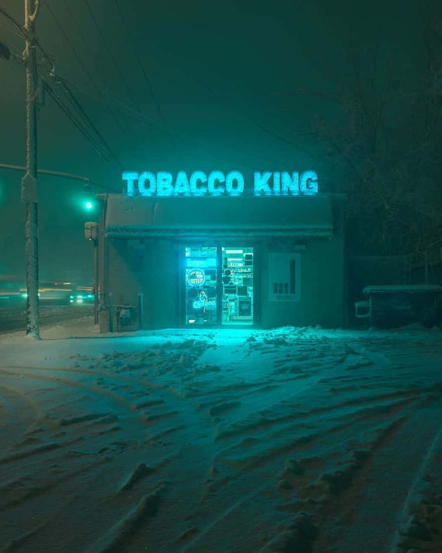 在積雪的冬夜中，Tobacco King 發光的藍色霓虹燈招牌。