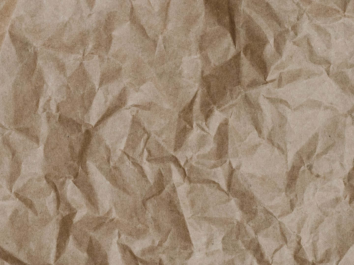 重疊折痕的羊皮紙背景 壁紙 — 一張皺巴巴的棕色紙張特寫，帶有深深的摺痕和柔和陰影，營造出觸感有機質感。
