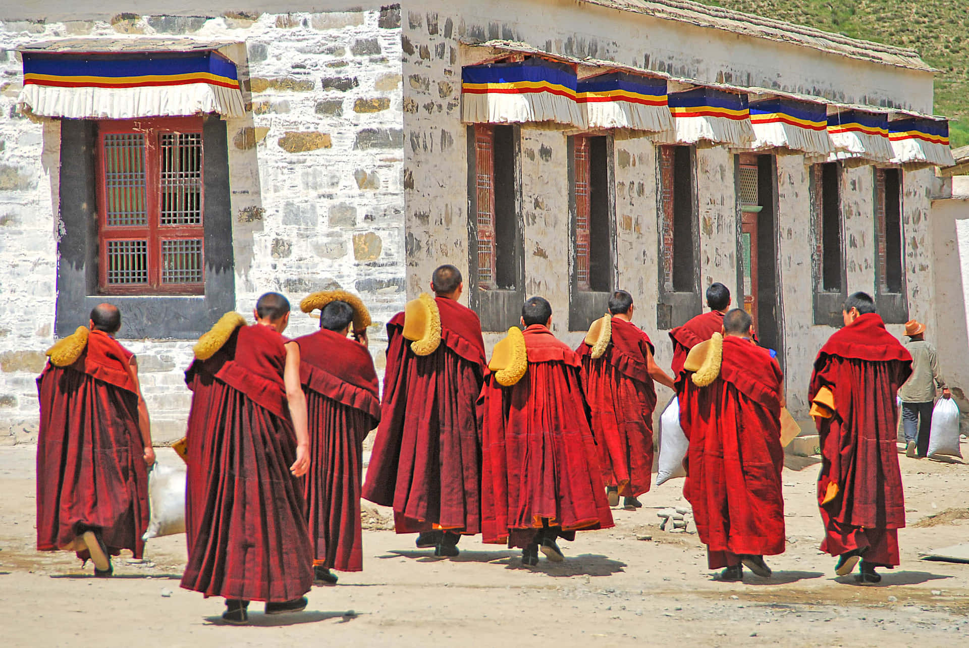 身穿紅色僧袍的僧侶遠離石頭寺院建築。