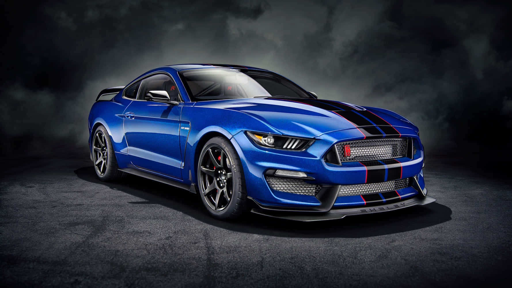 在黑暗的工作室環境中，帶有黑色條紋的藍色Shelby Mustang GT500。