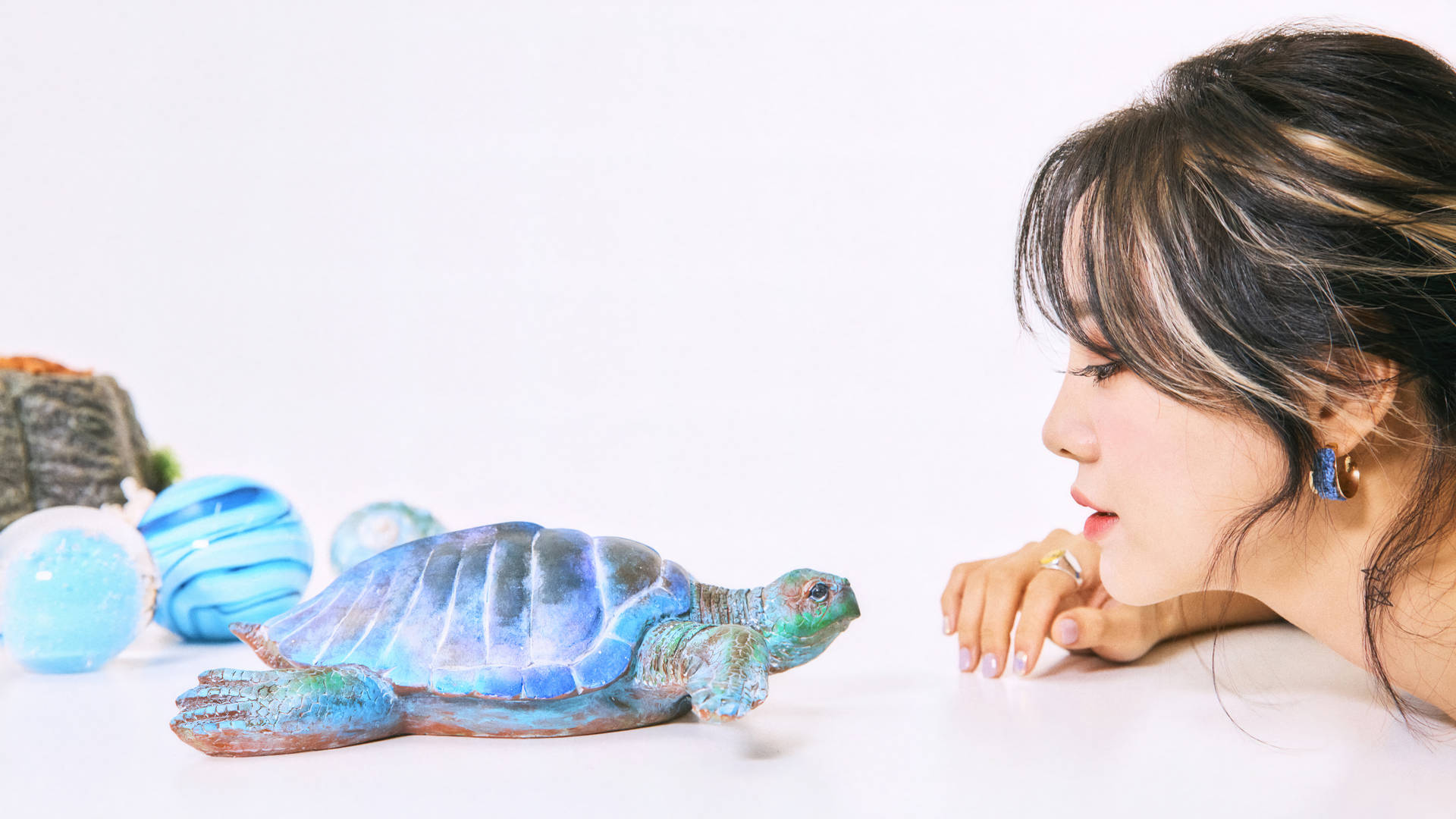 女士仔細看著白色桌子上的一個藍綠色烏龜雕像。