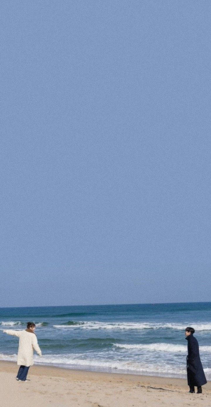 兩個人在海灘上觀看黃昏時的海洋。