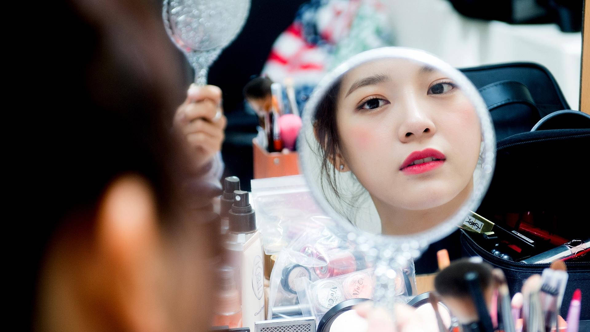 女性在鏡子前化妝，周圍環繞著美容產品。