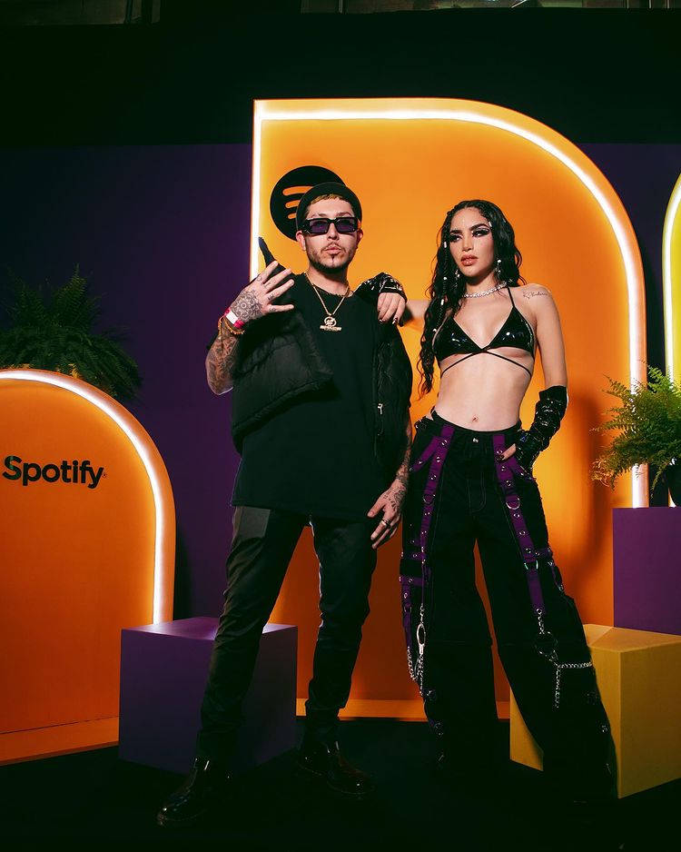 兩位音樂家在帶有發光橙色和紫色裝飾的Spotify活動中擺姿勢。