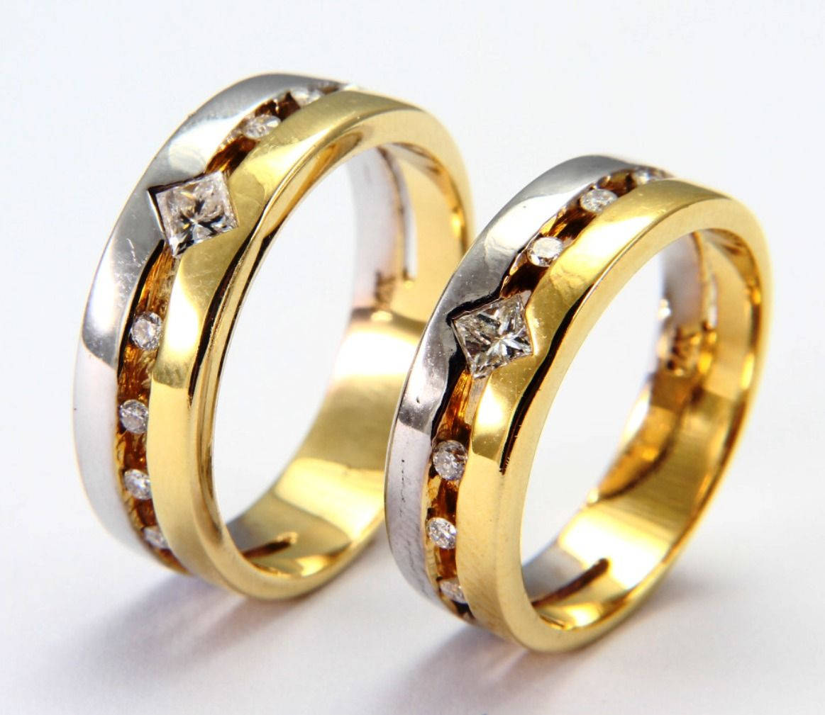金婚戒配銀飾 壁紙 — 兩隻金色和銀色的結婚戒指，帶有鑽石點綴，並排放在白色表面上。