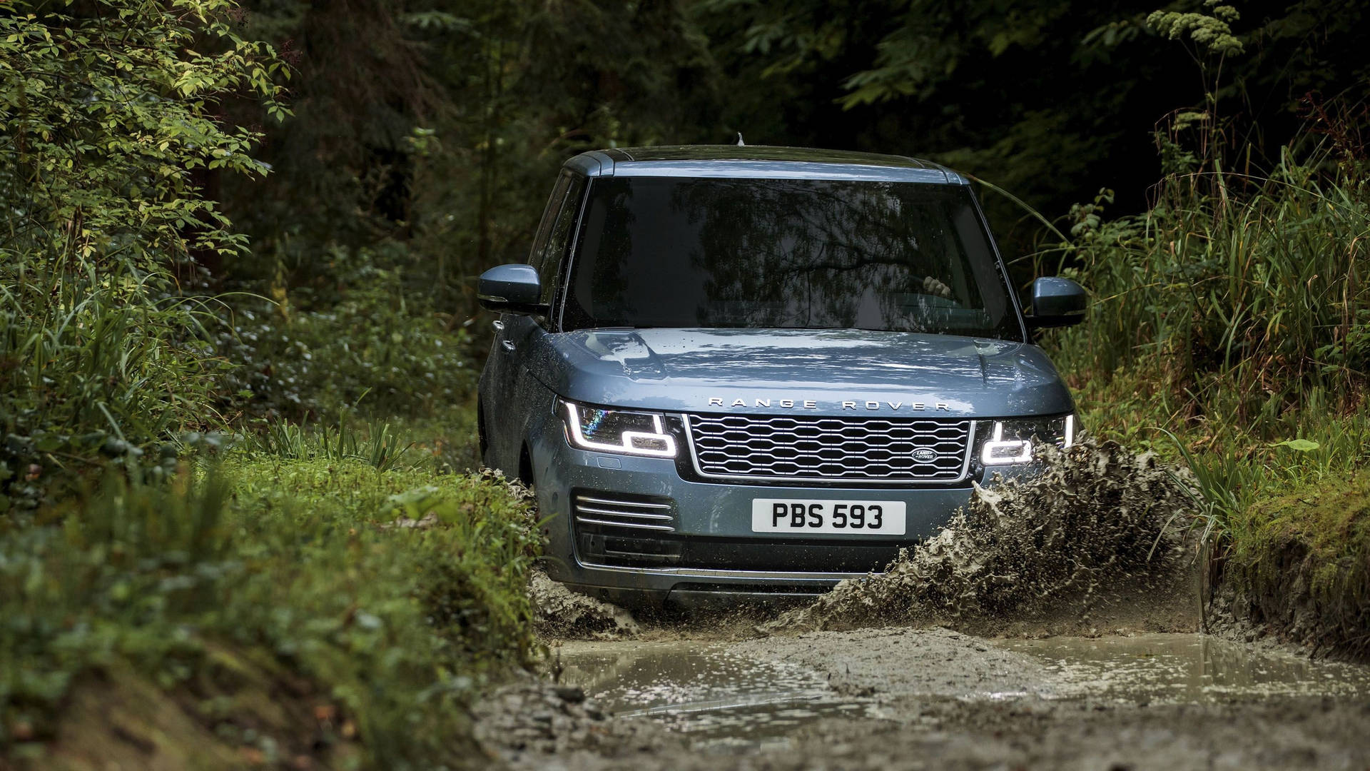 銀色 Range Rover 在泥濘森林小徑上行駛。