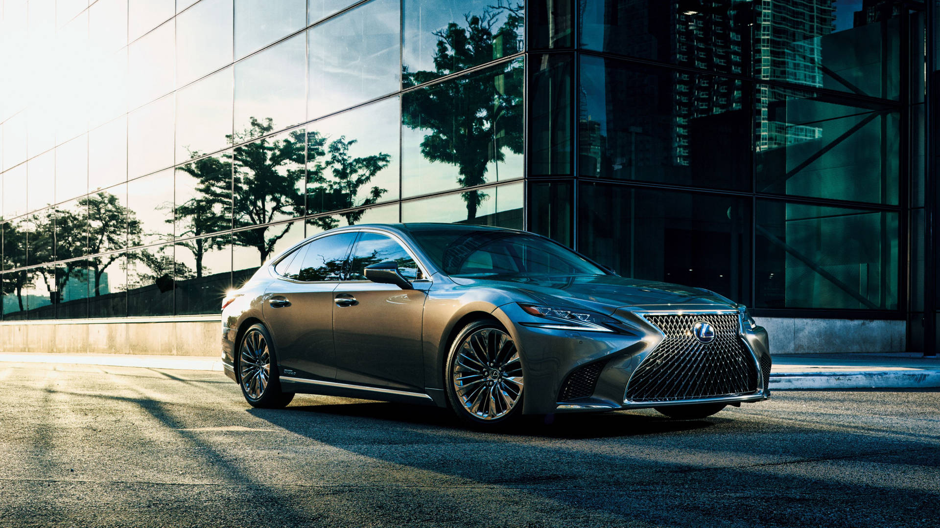 銀色 Lexus 房車停泊在帶有玻璃建築倒影的城市街道上。