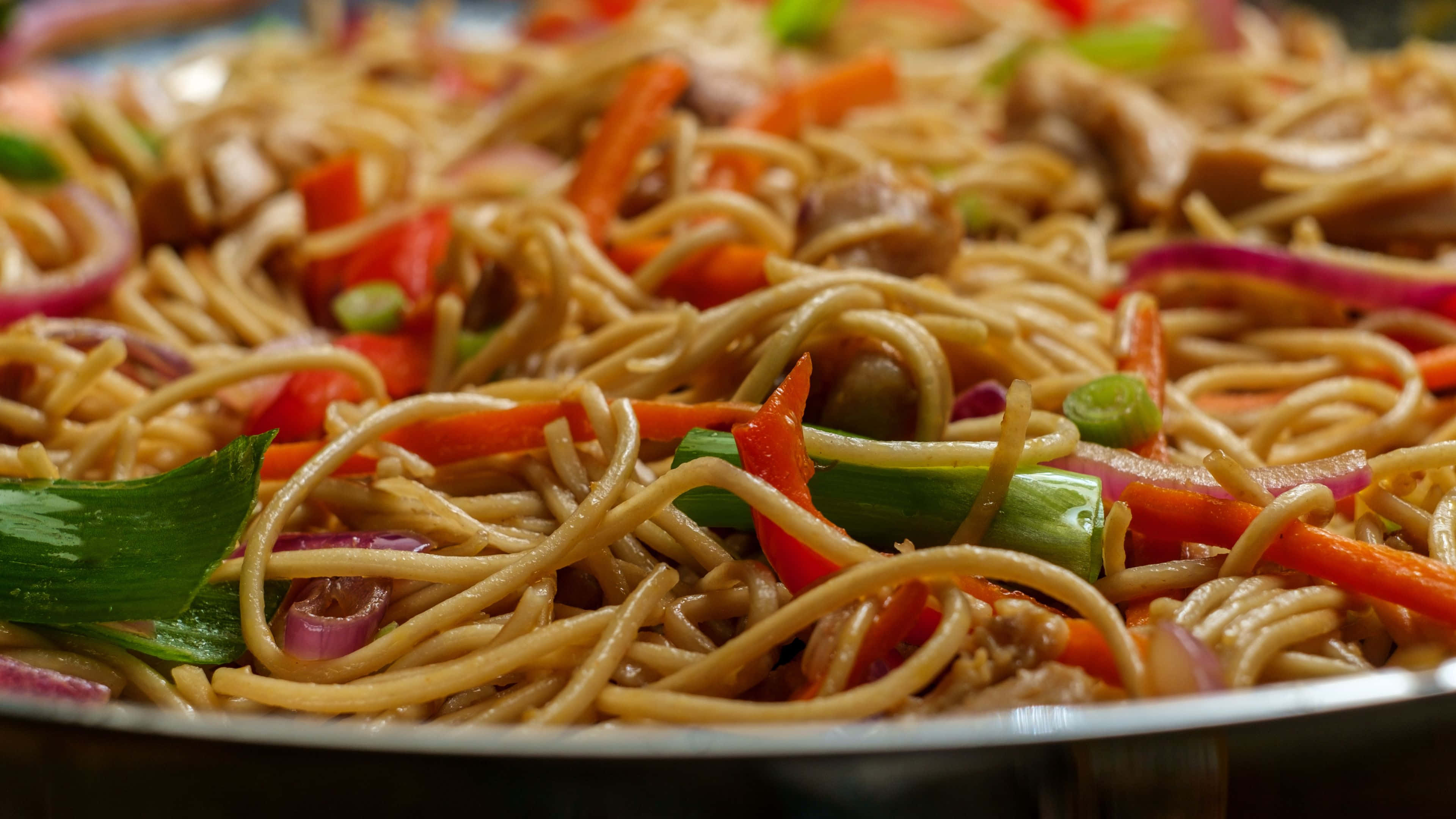 Noodles 桌布 壁紙 — 金屬碗中蒸氣騰騰的炒麵，搭配雞肉和色彩繽紛的蔬菜特寫。