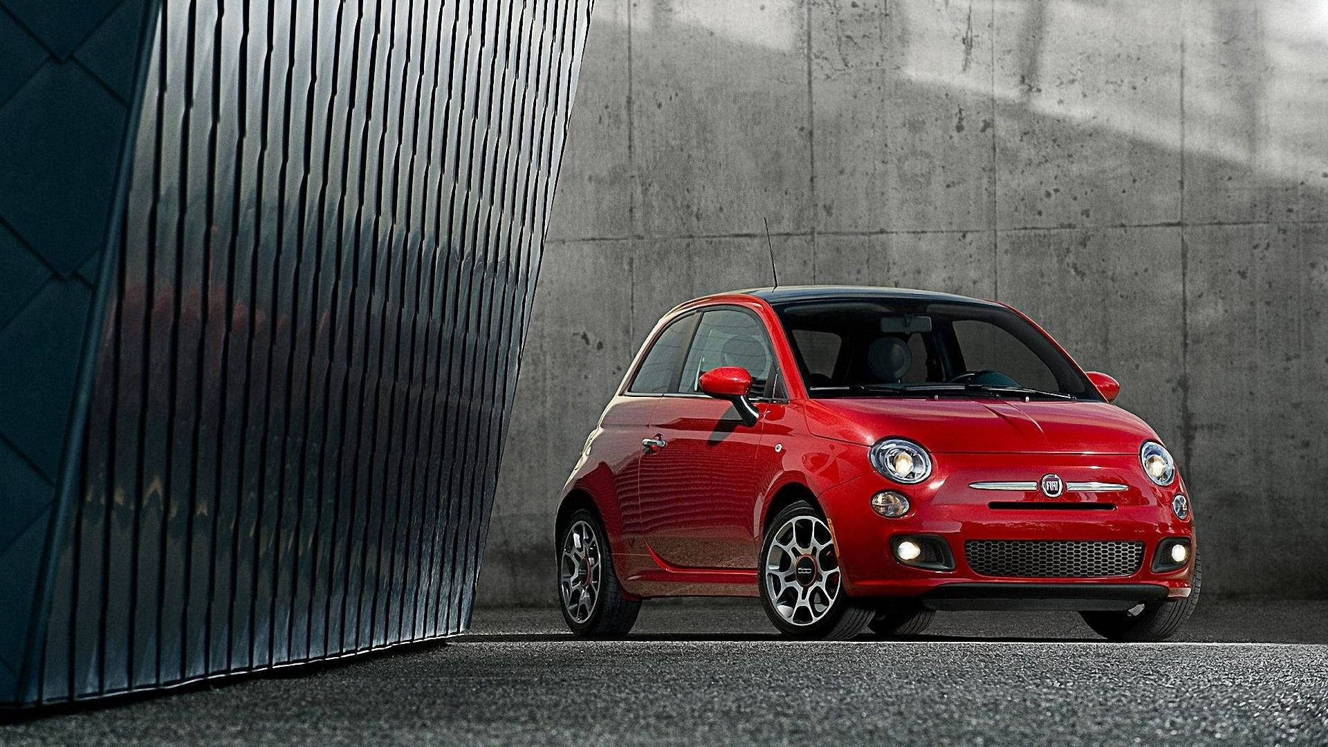 紅色Fiat 500停放在混凝土和金屬牆壁旁。
