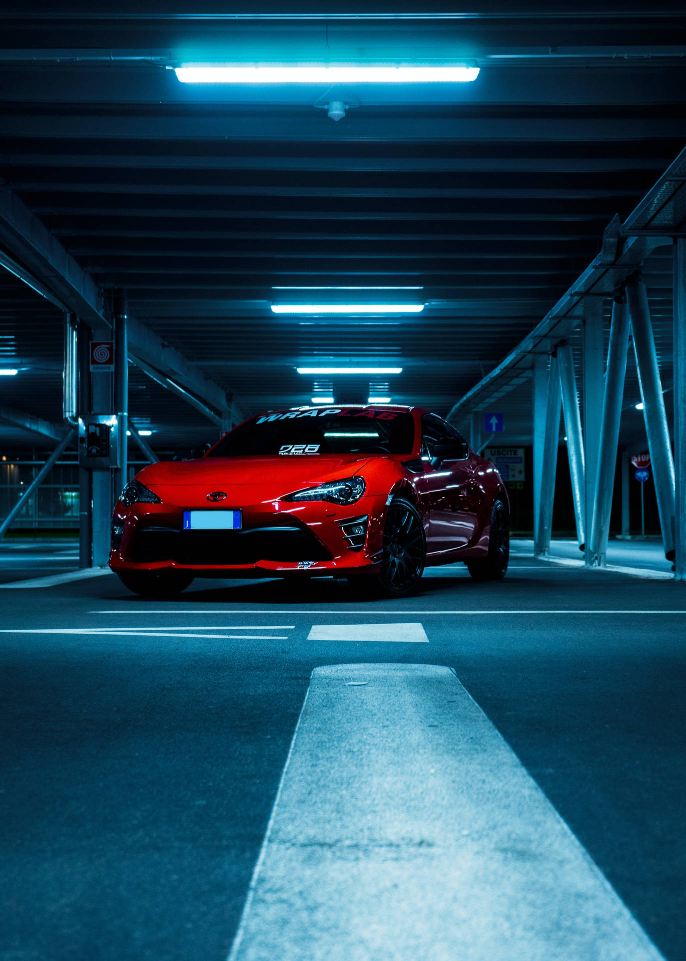 夜晚在藍色燈光的地下車庫中停放的紅色跑車。