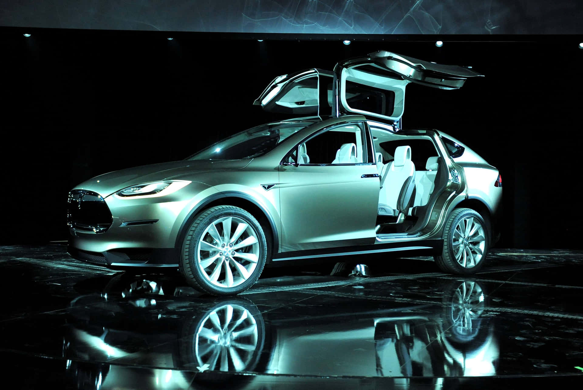 銀色 Tesla Model X，在藍色燈光下的反射舞台上打開車門。