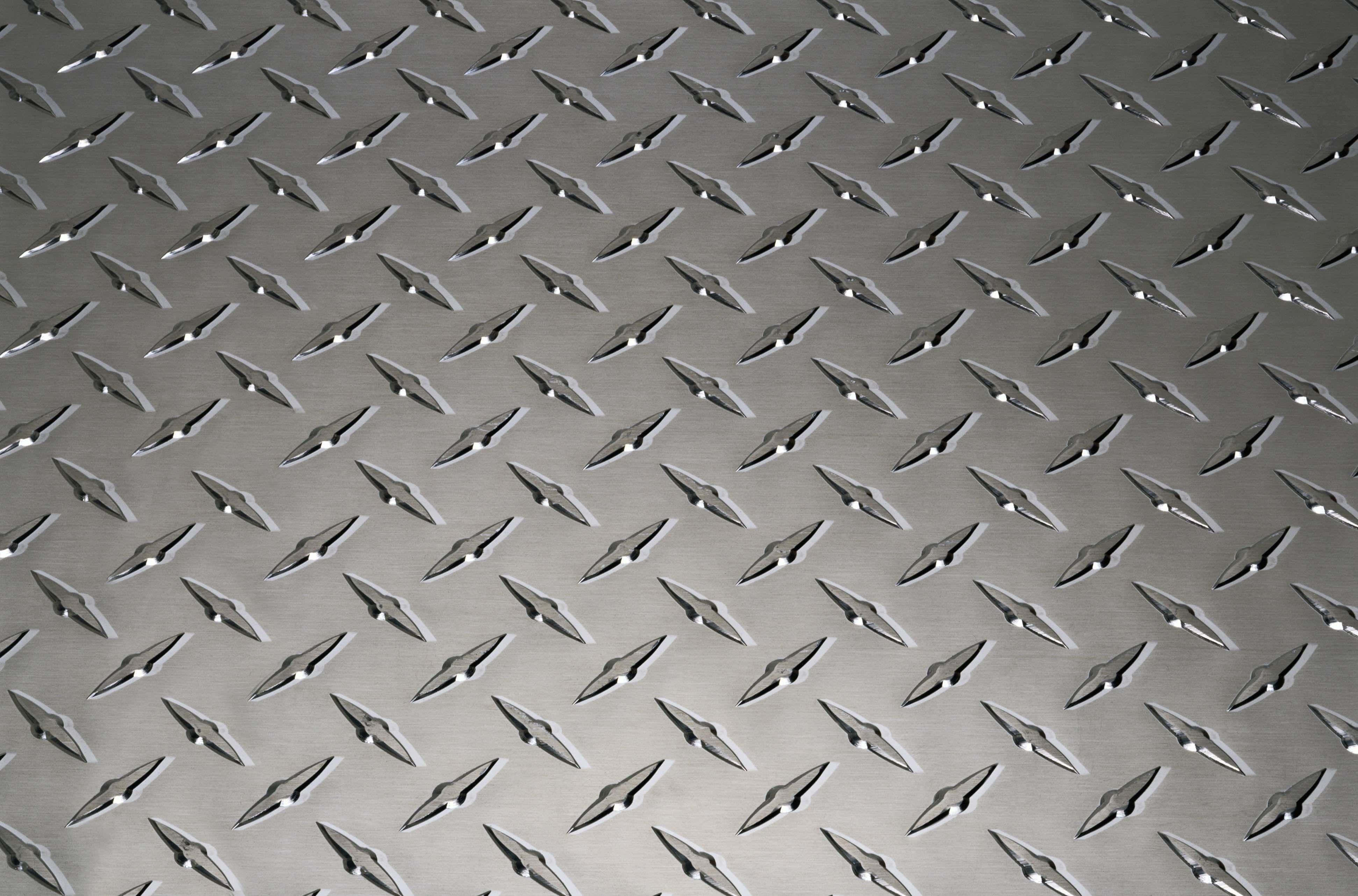 Diamond Plate 桌布 壁紙 — 金屬菱形紋板表面的特寫，帶有重複的凸起菱形圖案和拉絲銀色飾面。