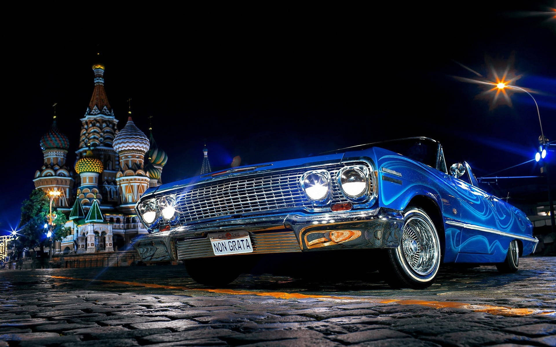 金屬藍色雪佛蘭Impala 1967 壁紙 — 一輛充滿活力的藍色經典敞篷車在聖巴西爾大教堂前的夜燈下閃閃發光。