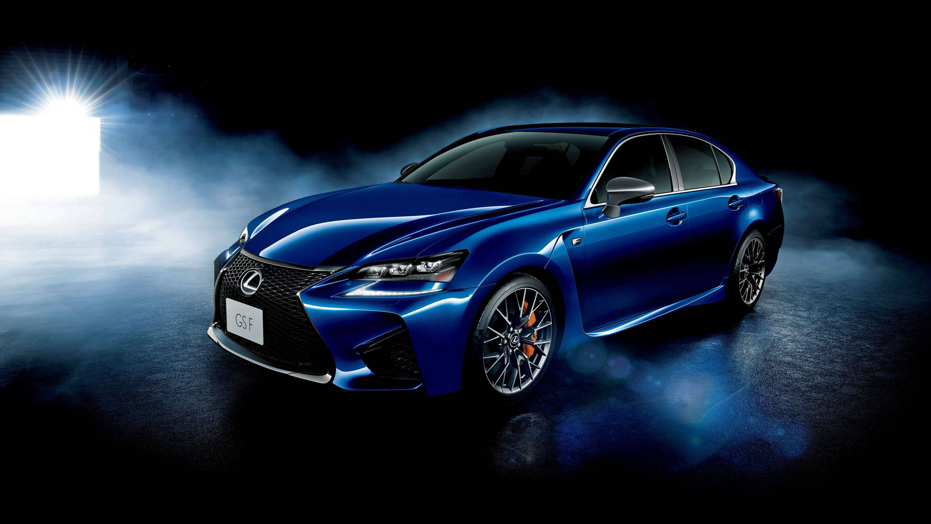藍色Lexus GS F轎車在煙霧瀰漫的黑暗攝影棚中被聚光燈照亮。