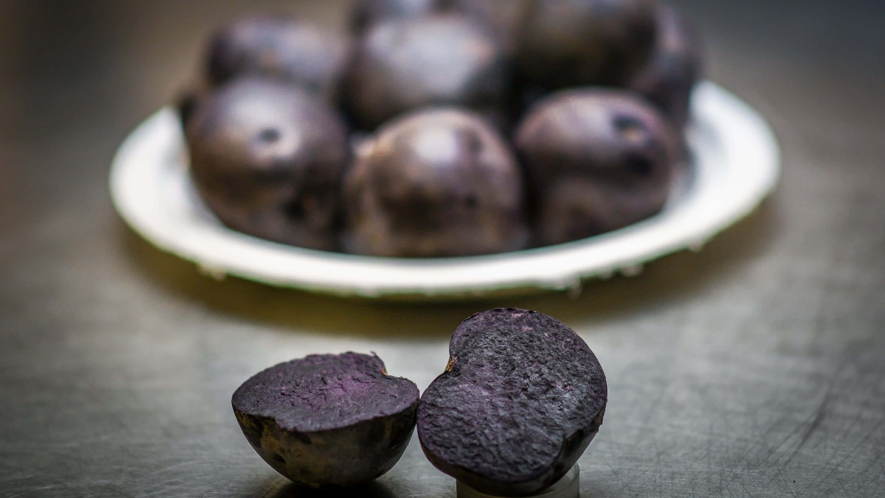Purple Potato 桌布 壁紙 — 金屬表面上嘅紫色甜菜切半特寫，後面有模糊嘅成個甜菜碟。