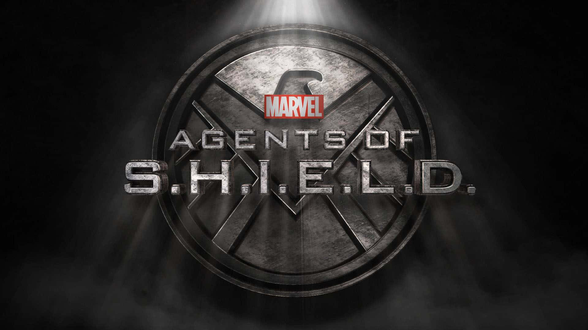 shield 桌布 壁紙 — 金屬質感的S.H.I.E.L.D.標誌在聚光燈下發光，背景為黑暗煙霧瀰漫，並帶有Marvel Agents of S.H.I.E.L.D.標題。