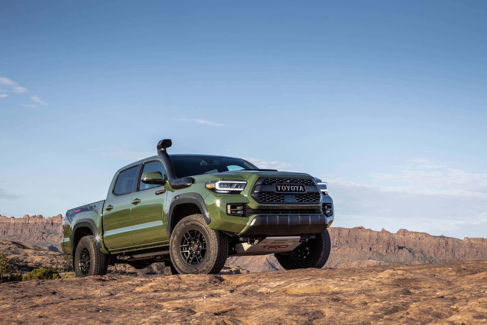 日落時分停在沙漠岩石上的橄欖綠色豐田 Tacoma TRD Pro。