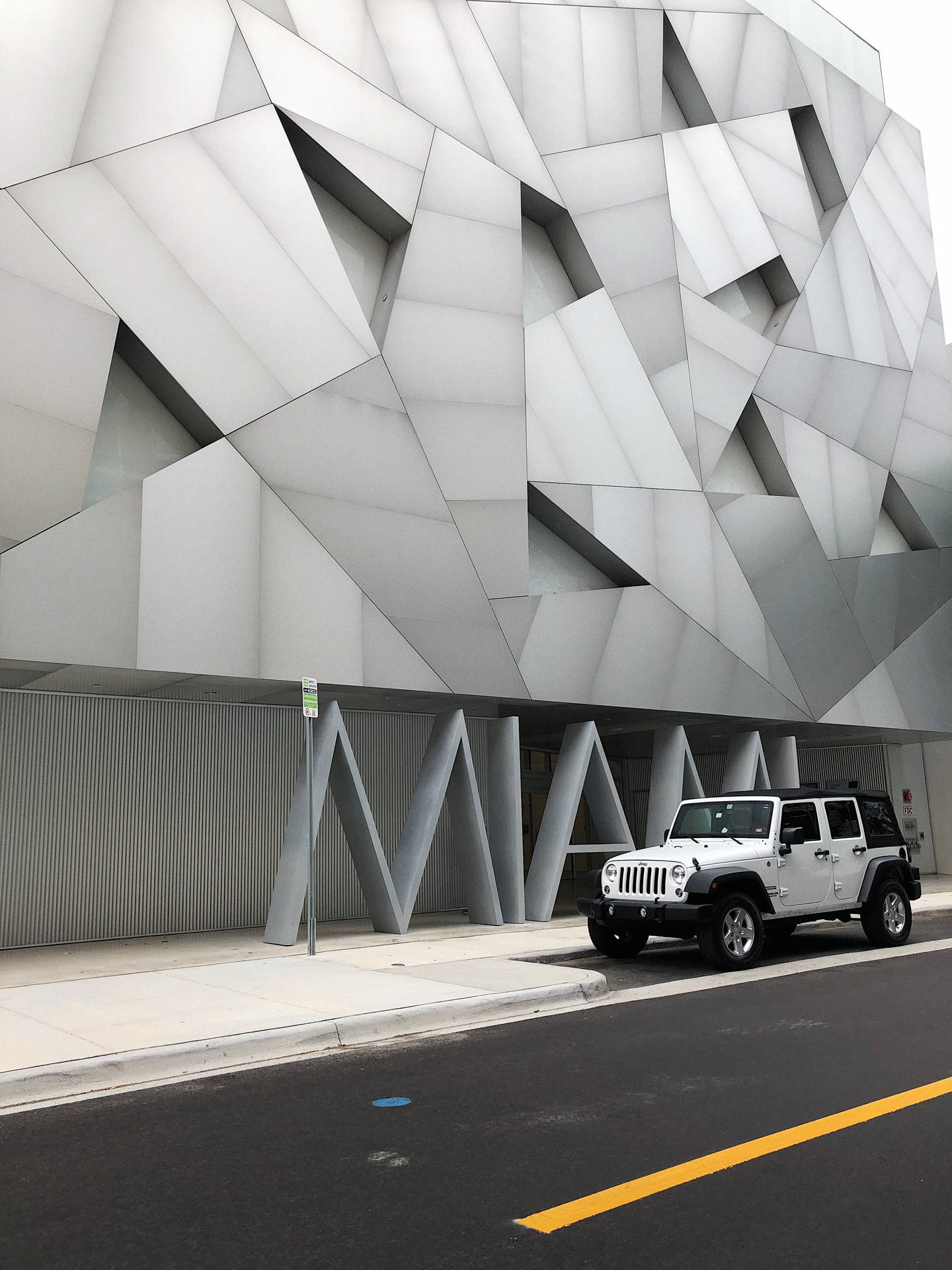 白色Jeep停在幾何現代建築前。