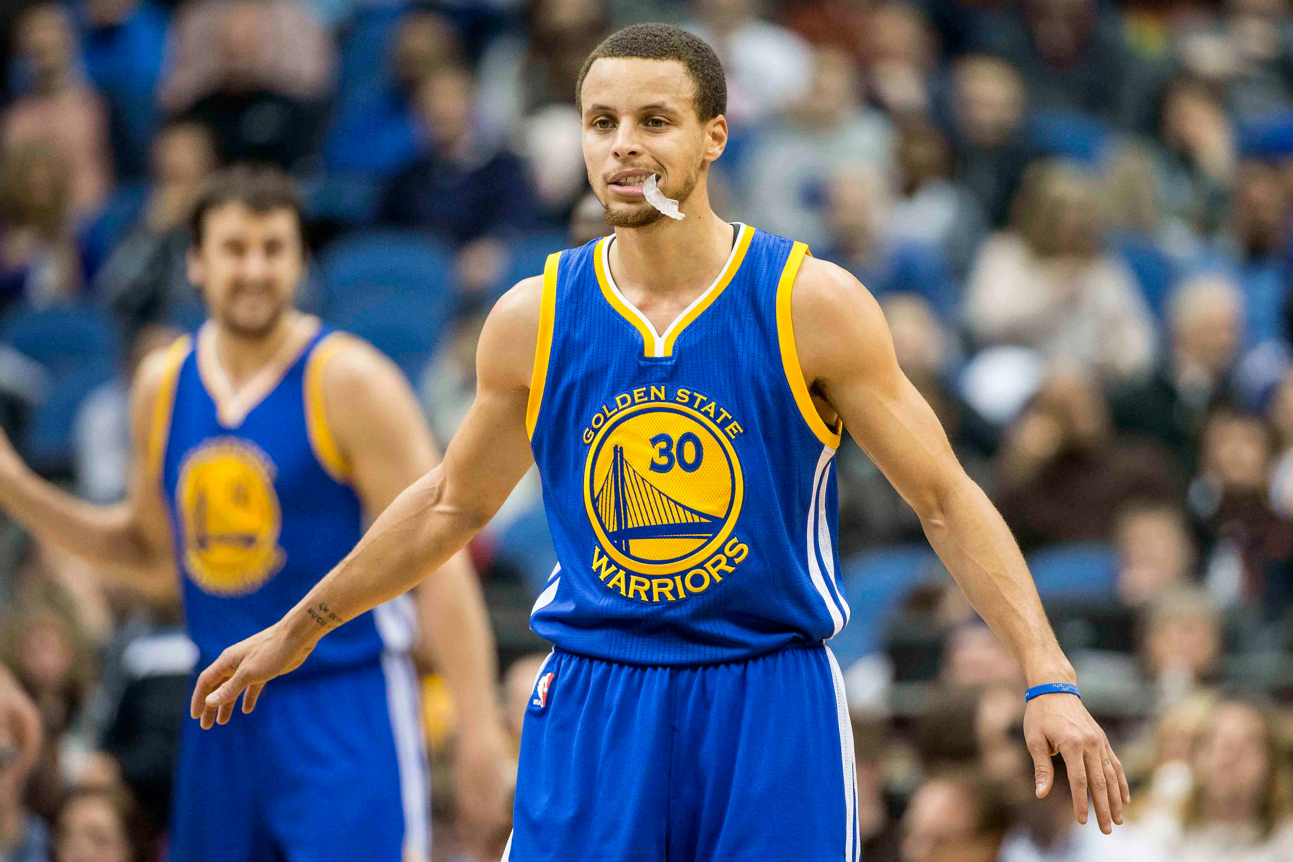 steph curry 桌布 壁紙 — 金州勇士隊球員史提芬居里身穿藍黃色30號球衣，站在籃球場上，背景有觀眾。
