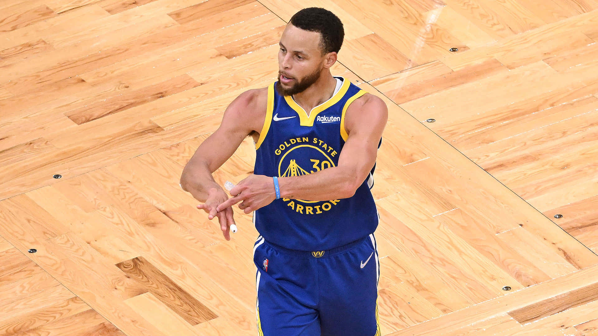 steph curry 桌布 壁紙 — 金州勇士隊球員史提芬居里身穿藍黃色球衣，在拋光木地板上運球。