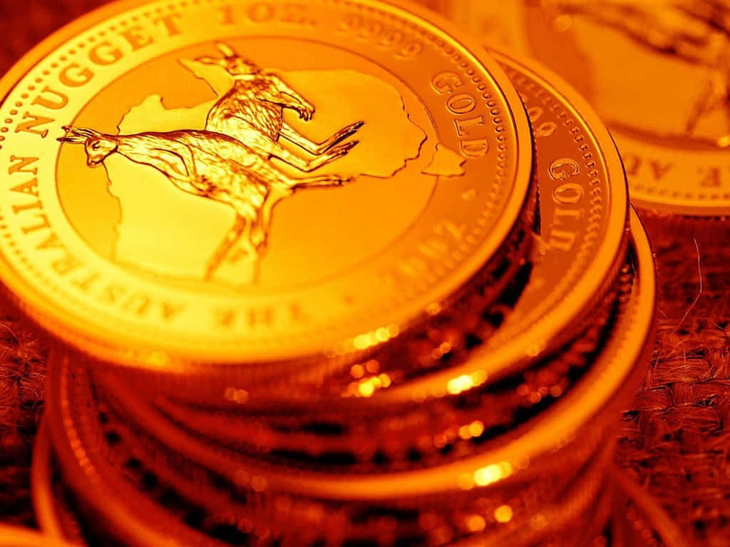 金幣堆疊 壁紙 — 一堆閃閃發光的澳洲金幣，上面有跳躍的袋鼠標誌，在溫暖的琥珀色燈光下。