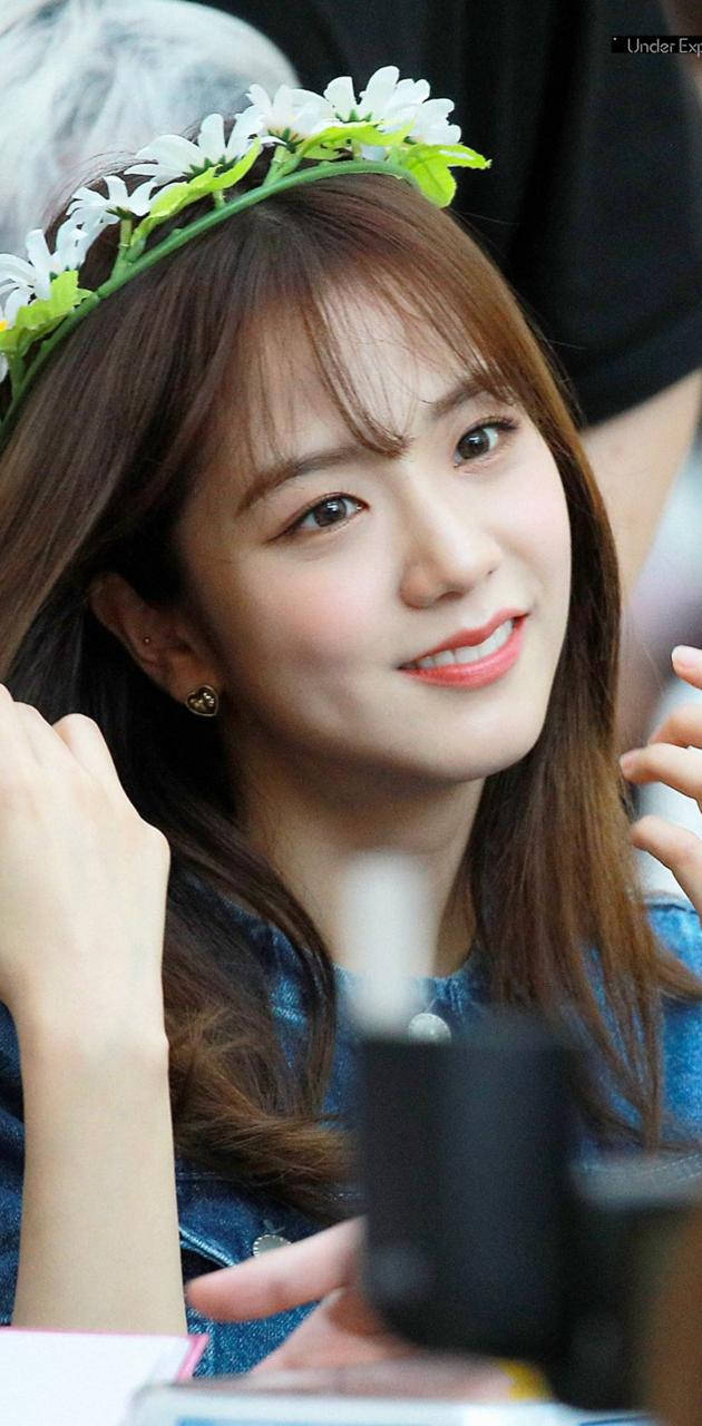 年輕女性戴著雛菊花冠和牛仔上衣溫暖微笑