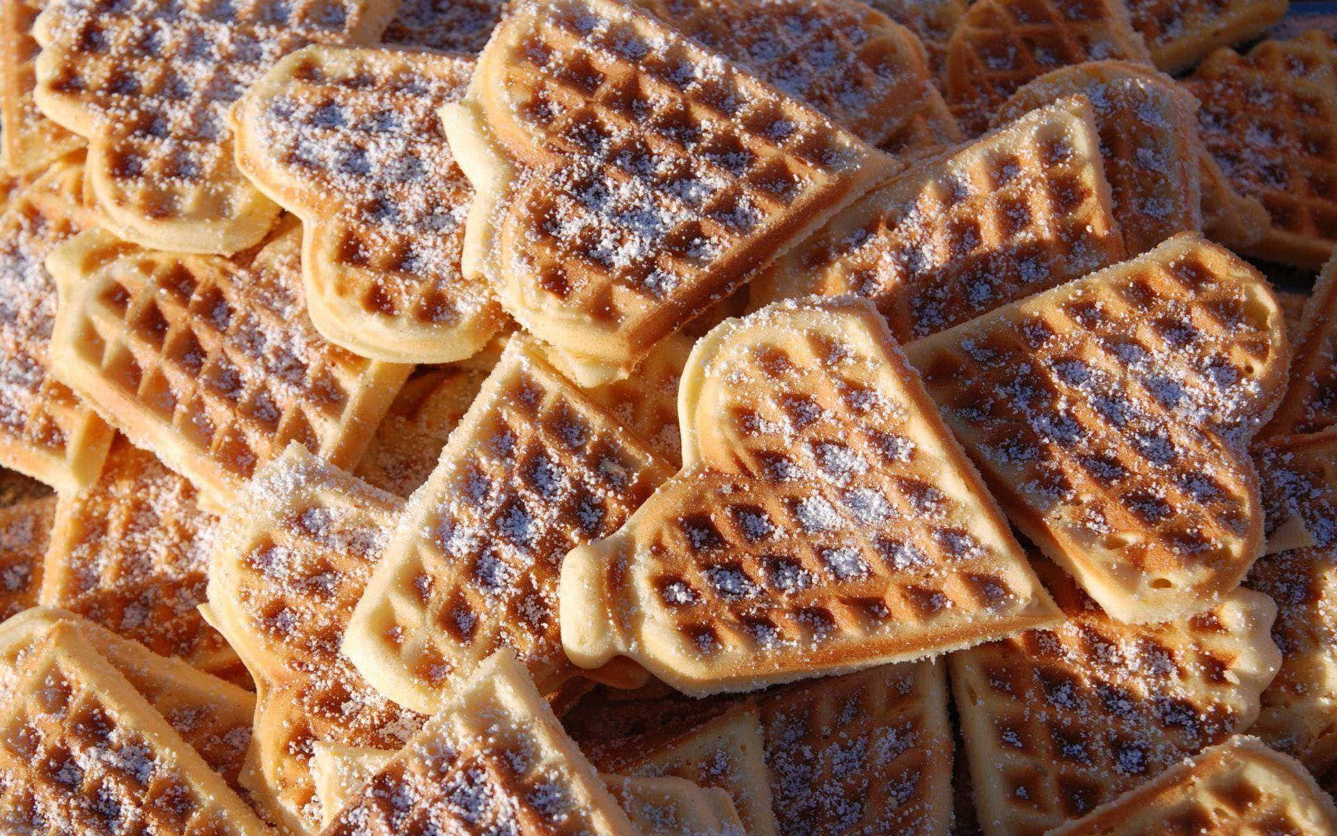 Waffle 桌布 壁紙 — 金棕色心形窩夫的特寫，撒上糖粉，誘人地堆疊在一起。