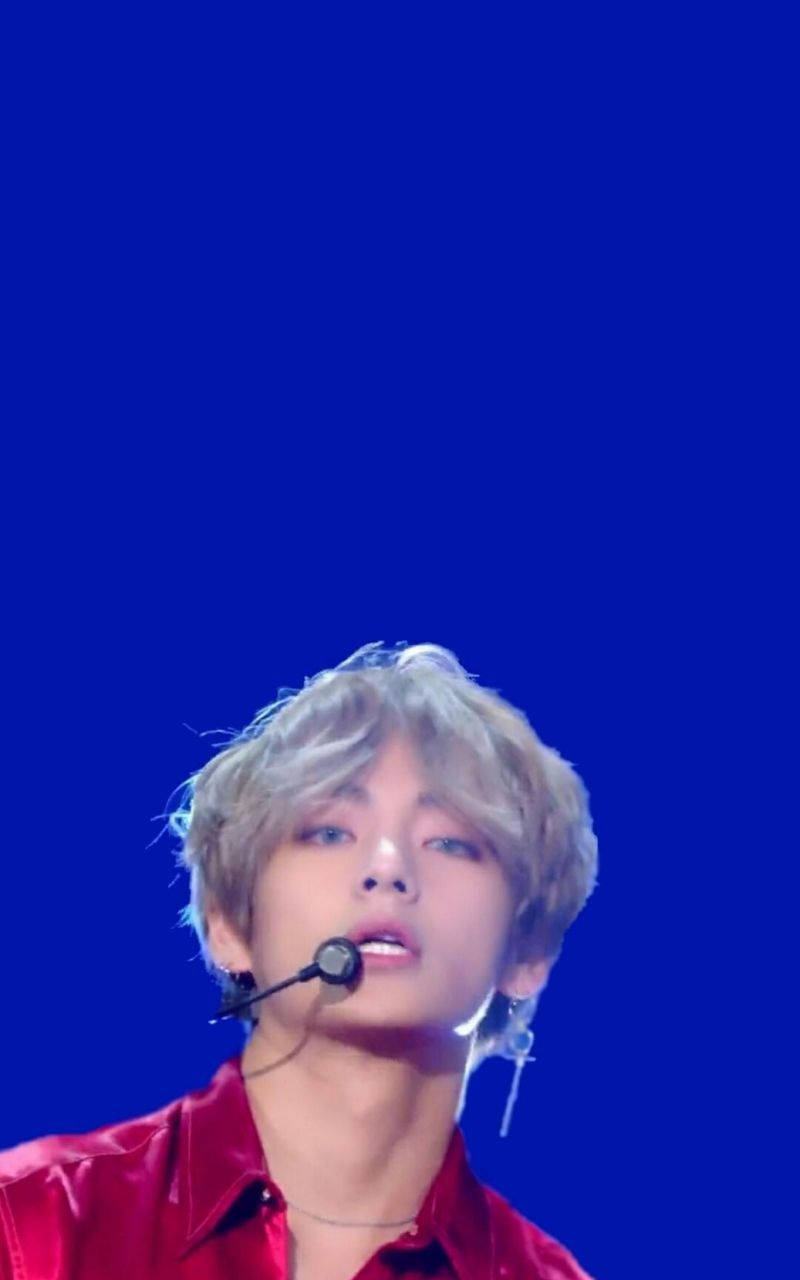 K-pop表演者身穿紅衫在藍色背景的舞台上唱歌。
