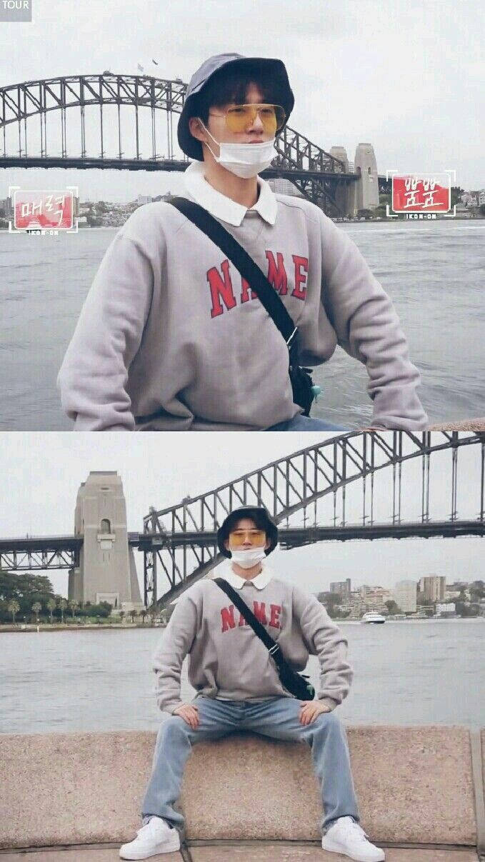 金漢彬 iKON - On 壁紙 — 一名身穿灰色運動衫和漁夫帽的人坐在石台上，背景是悉尼港灣大橋。